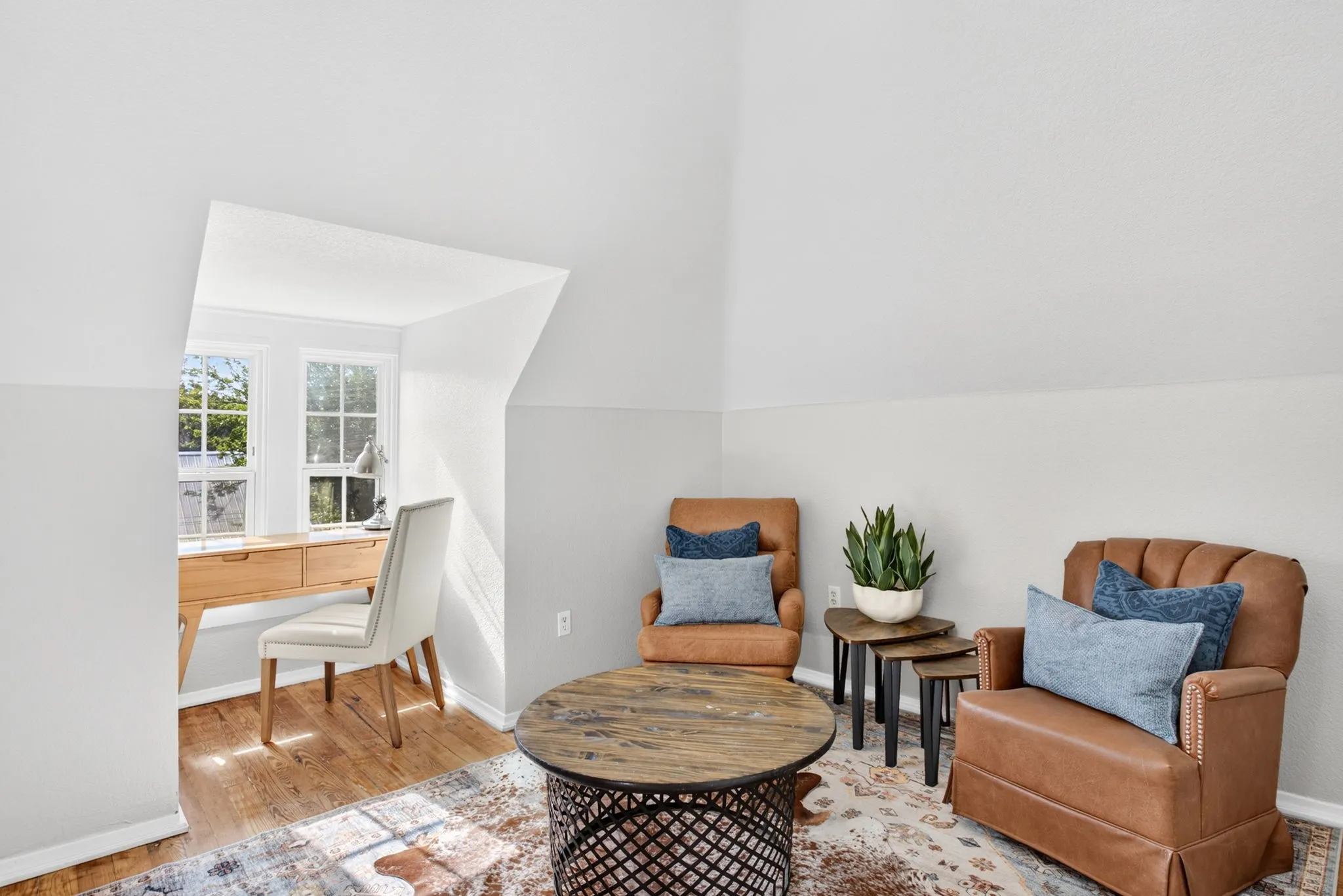 Attic space featuring wood-finish flooring, white walls, and a built-in alcove with two windows