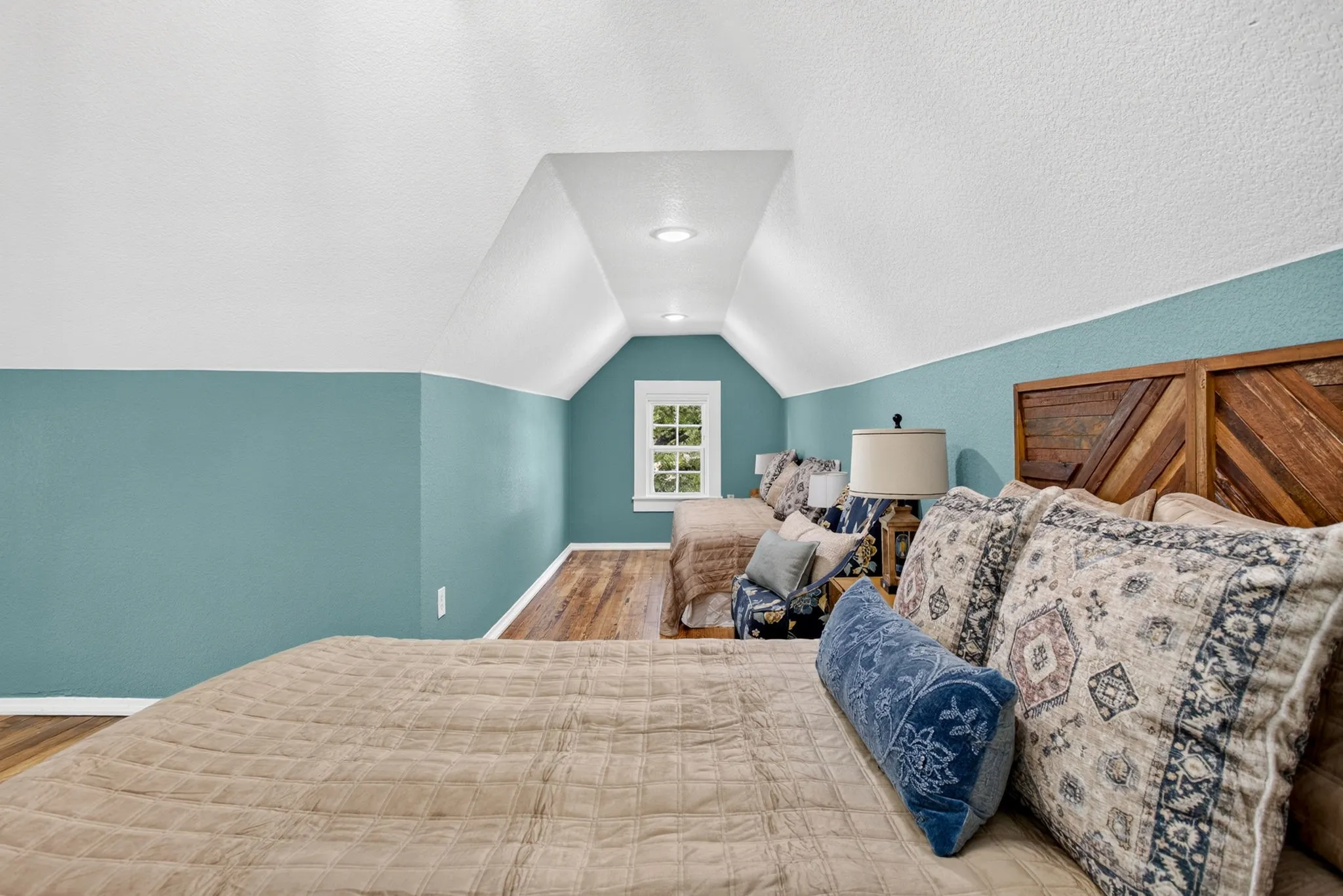 Attic room featuring sloped ceilings, recessed lighting, wood-finish flooring, and a window with grid detailing