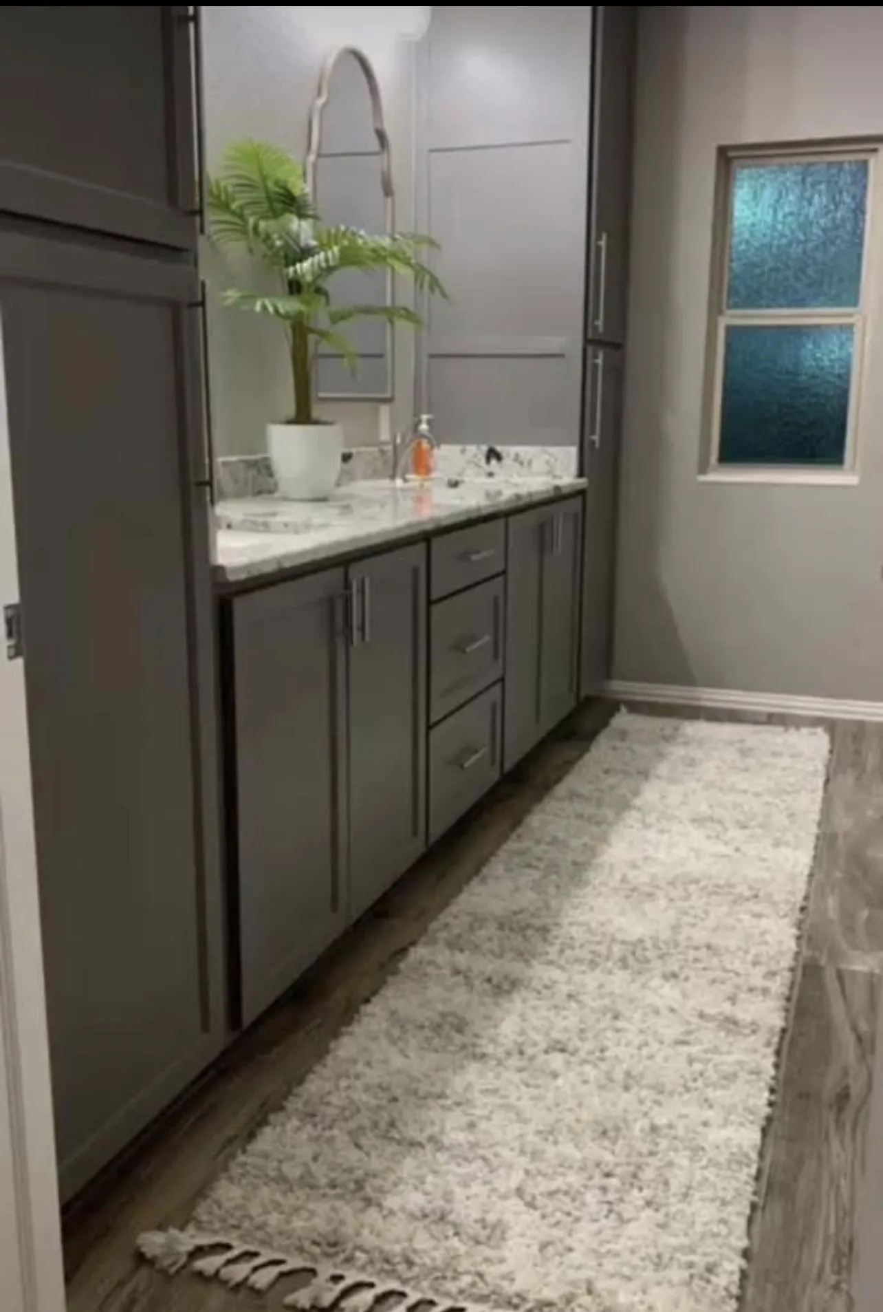 Contemporary vanity with gray cabinetry, white speckled countertop, and silver hardware