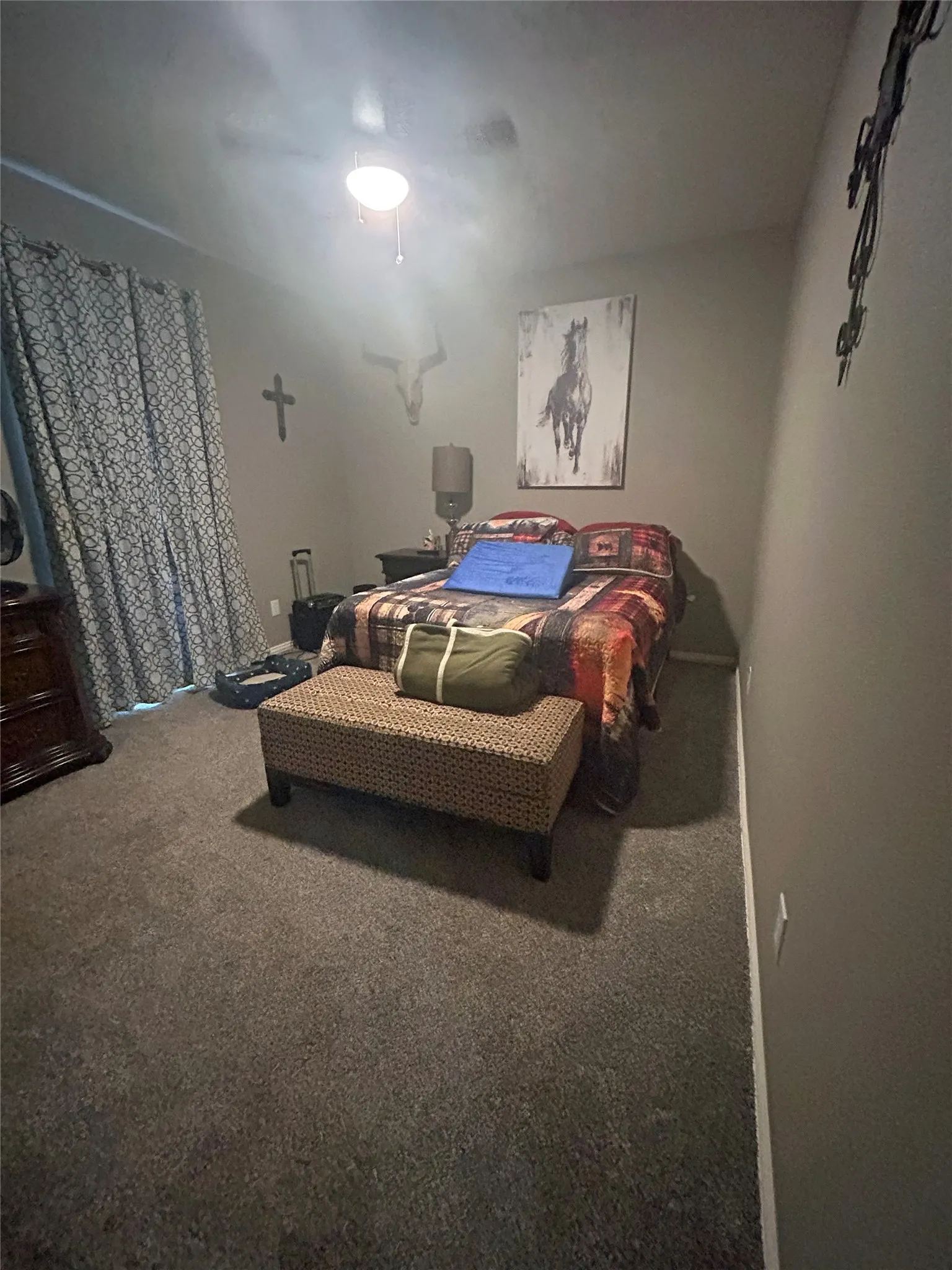 Carpeted interior room featuring a ceiling fan with integrated lighting, window with drapes, and neutral wall tones
