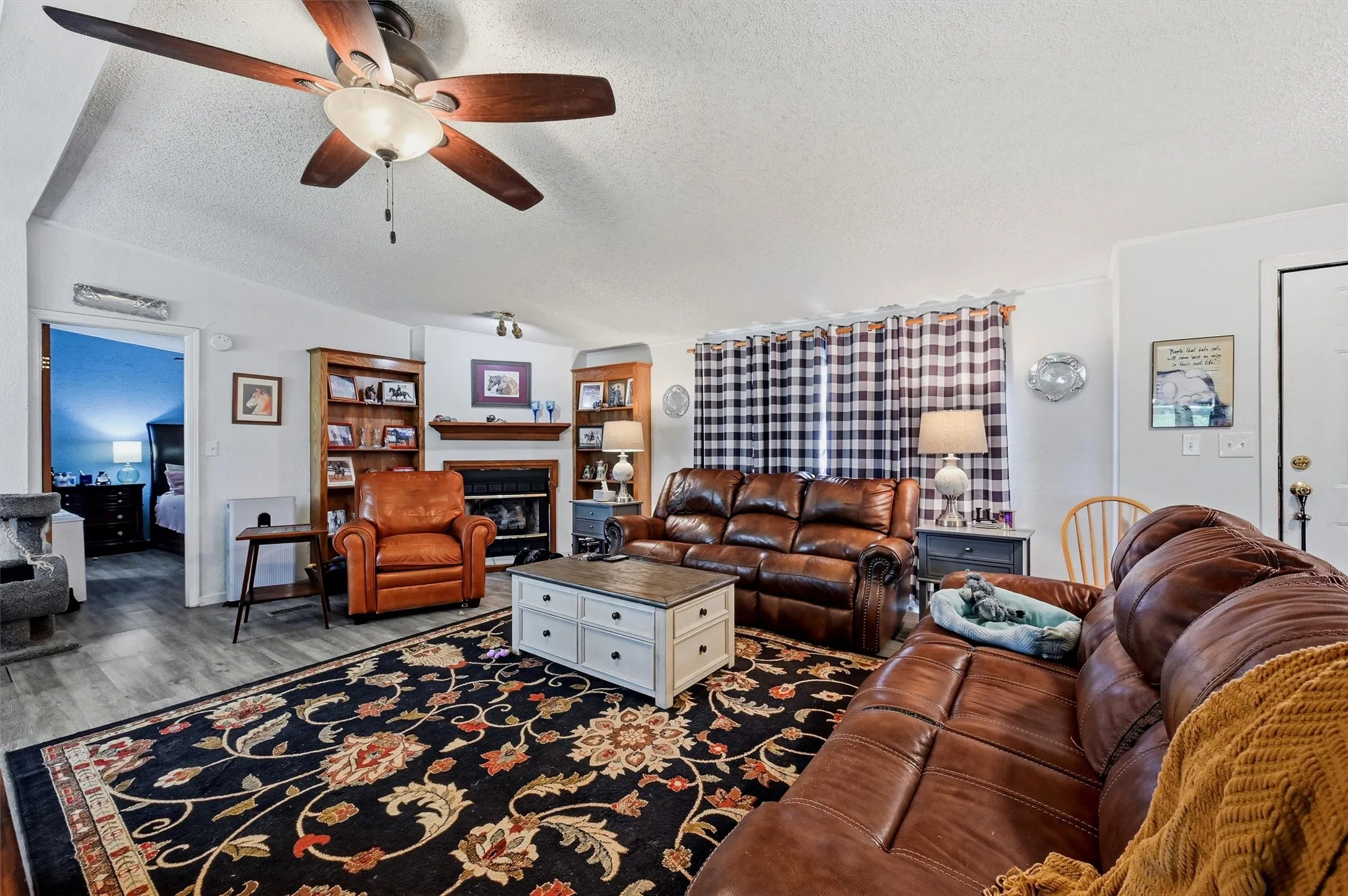 Living area featuring a ceiling fan with integrated lighting, and a fireplace with a wood mantle