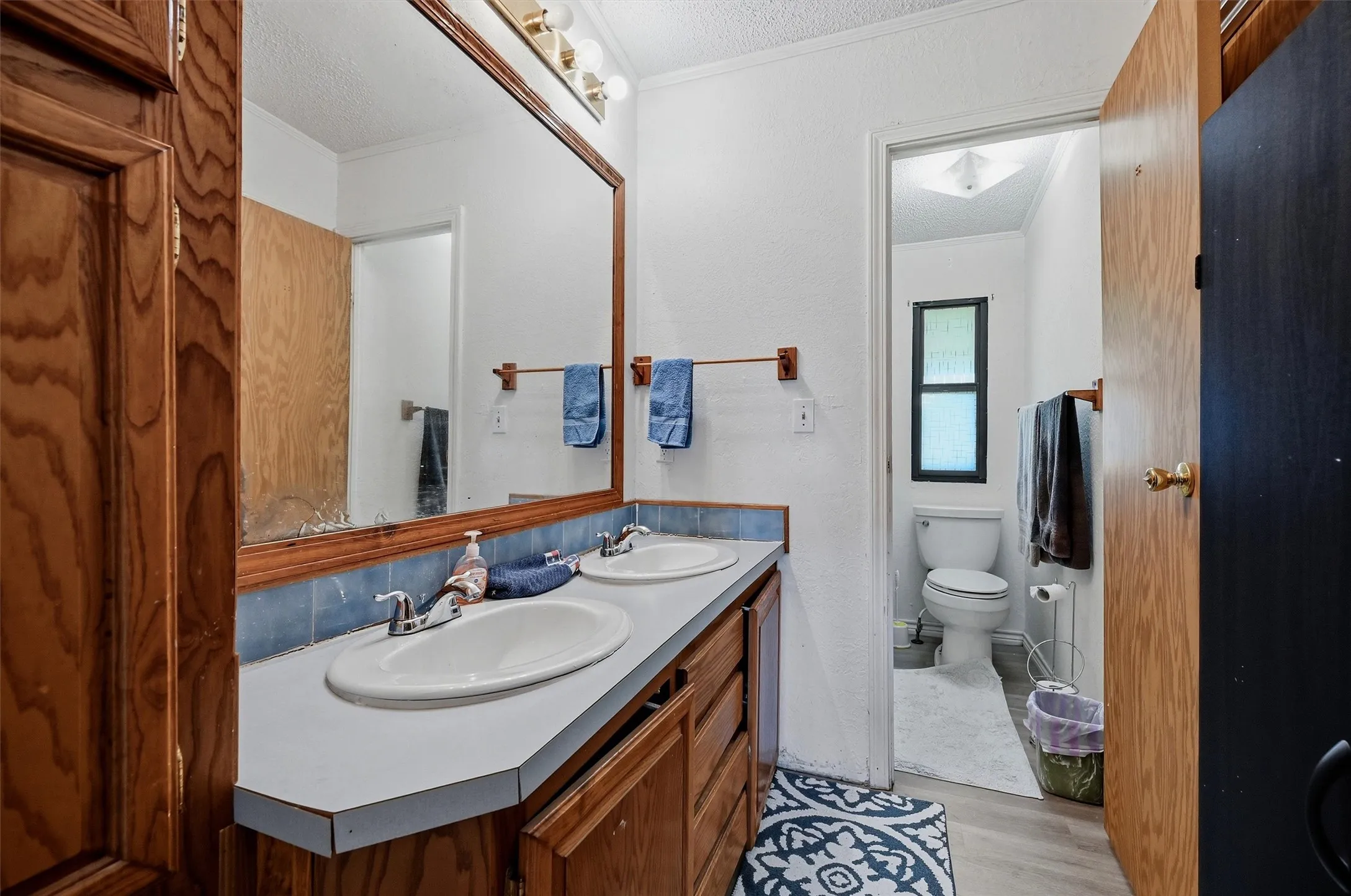 Double vanity with white countertops and oval sinks, set against a blue tiled backsplash