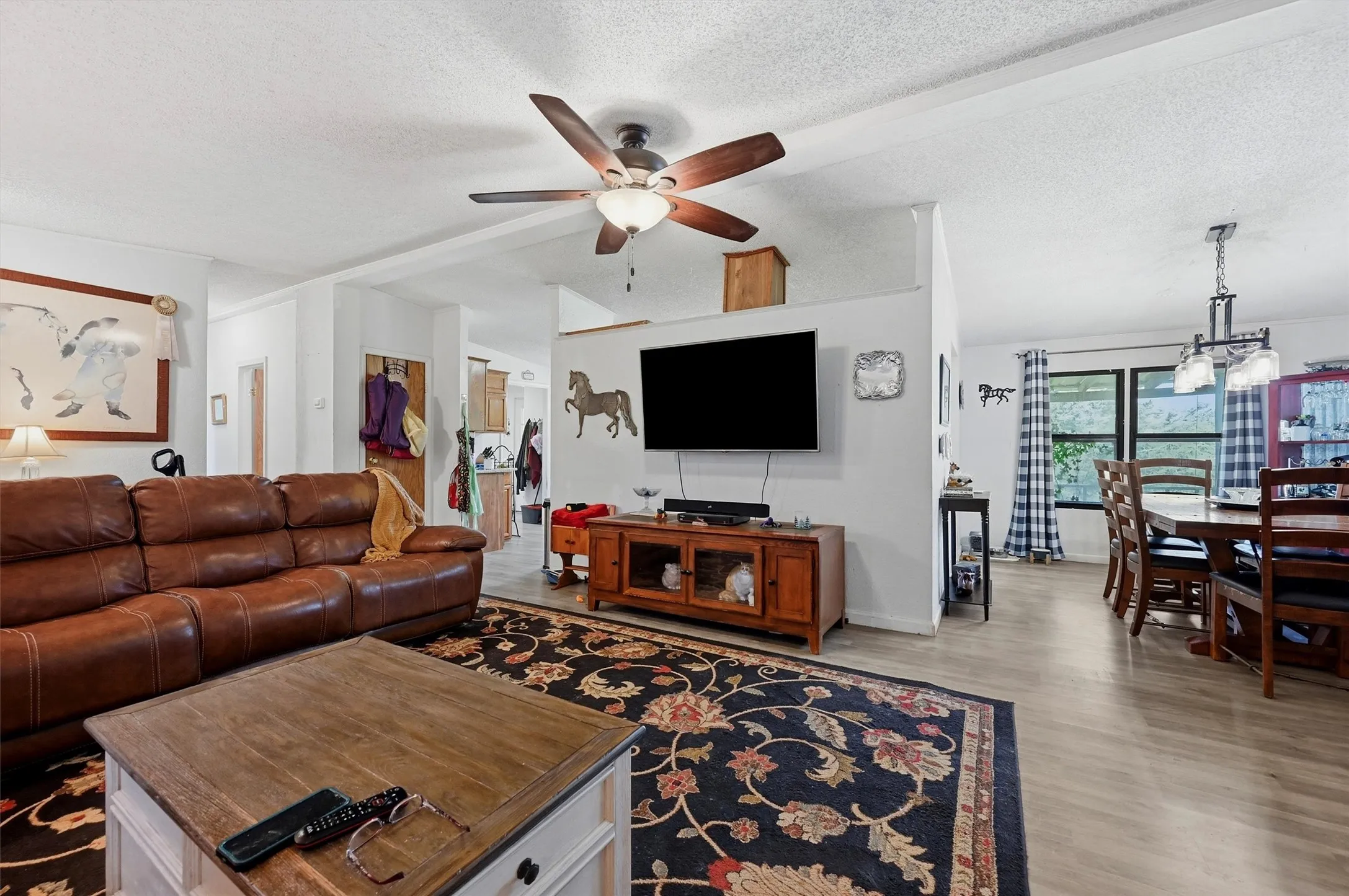Open-concept living area featuring a ceiling fan and dining space with a multi-bulb chandelier