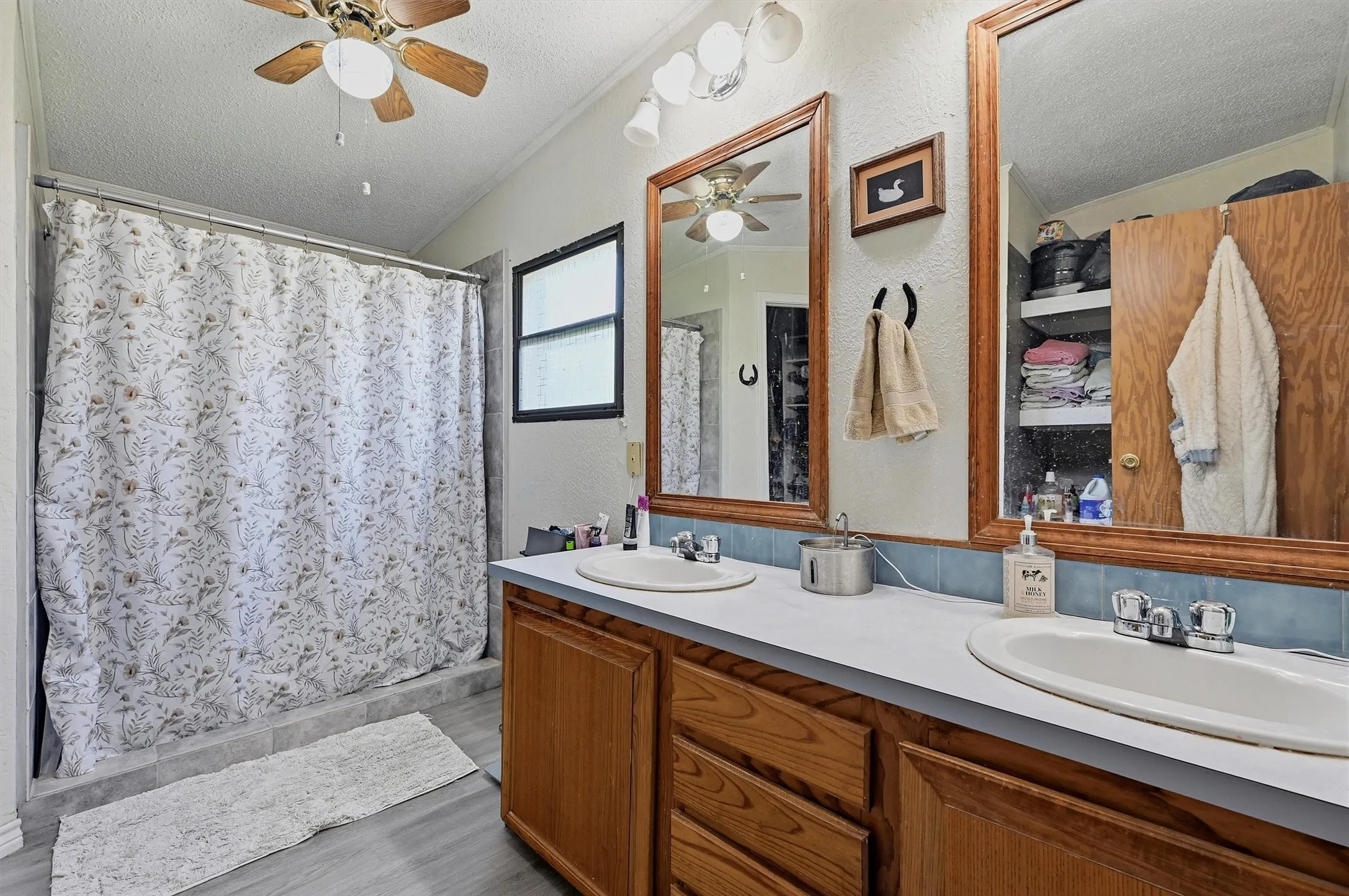 Double vanity with wood-finish cabinetry, dual oval sinks, and chrome fixtures