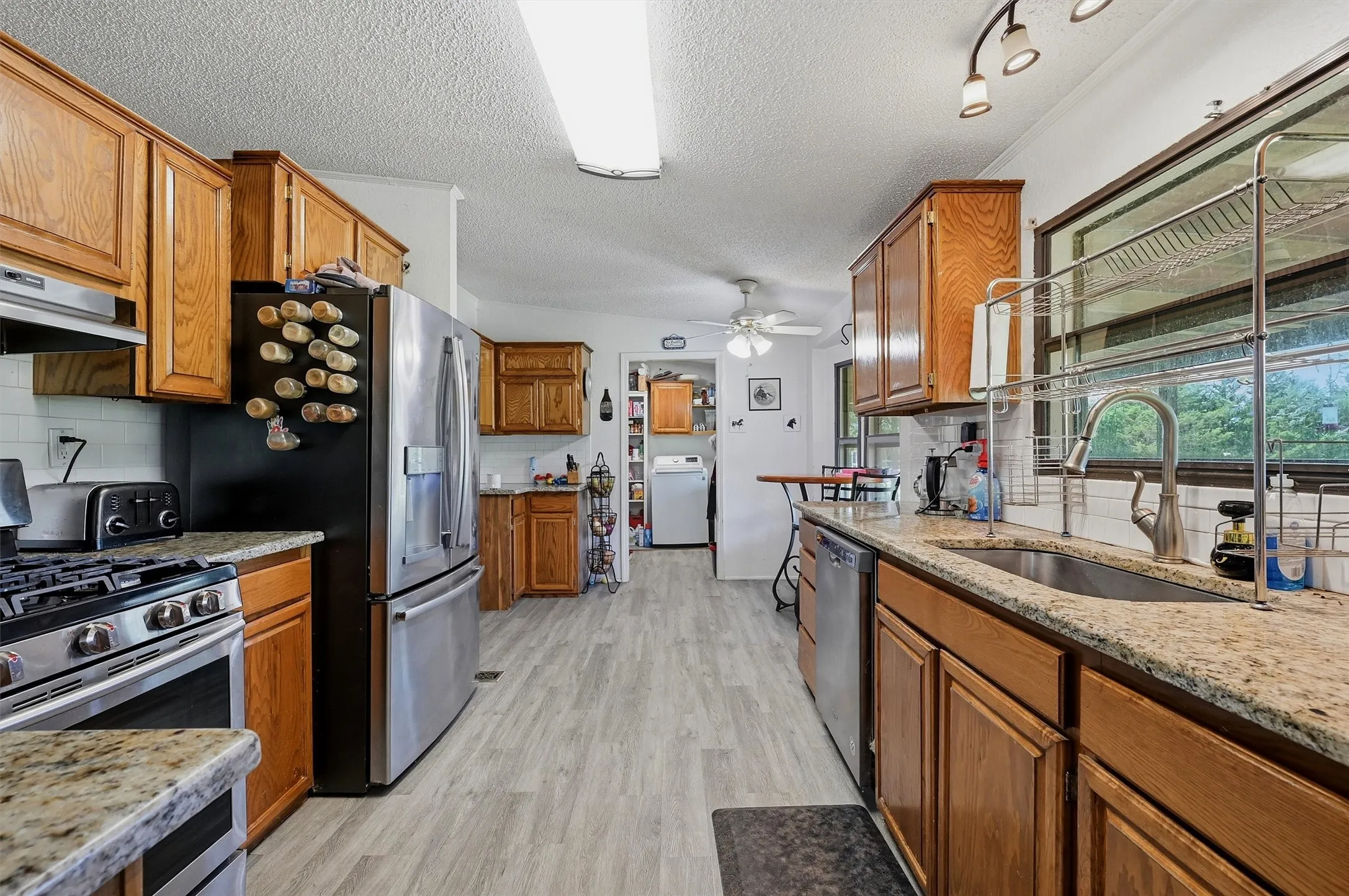 Kitchen featuring wood-finish cabinetry, granite countertops, stainless-steel appliances, and wood-look flooring