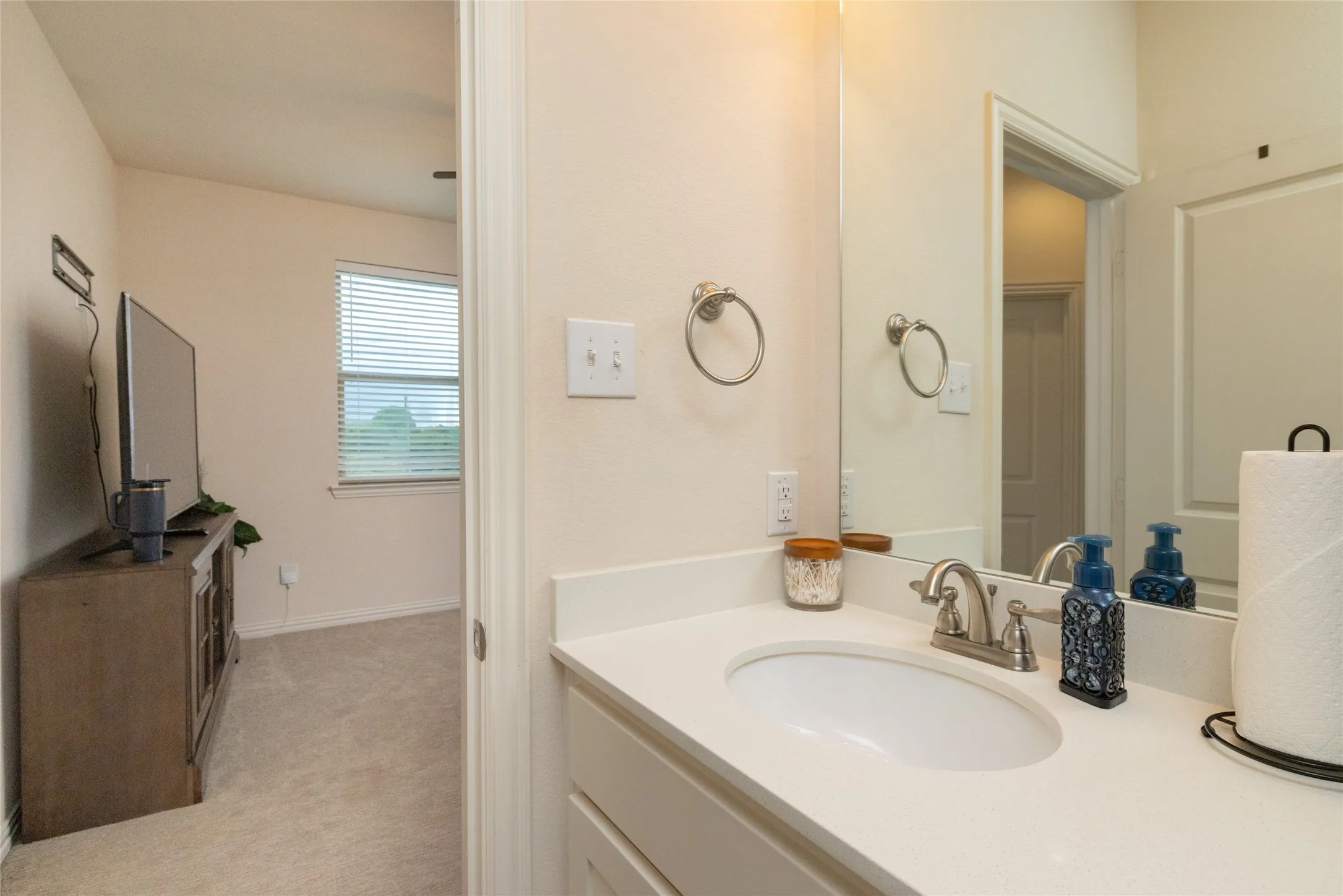 Vanity with integrated sink, brushed nickel faucet, and a large wall-mounted mirror