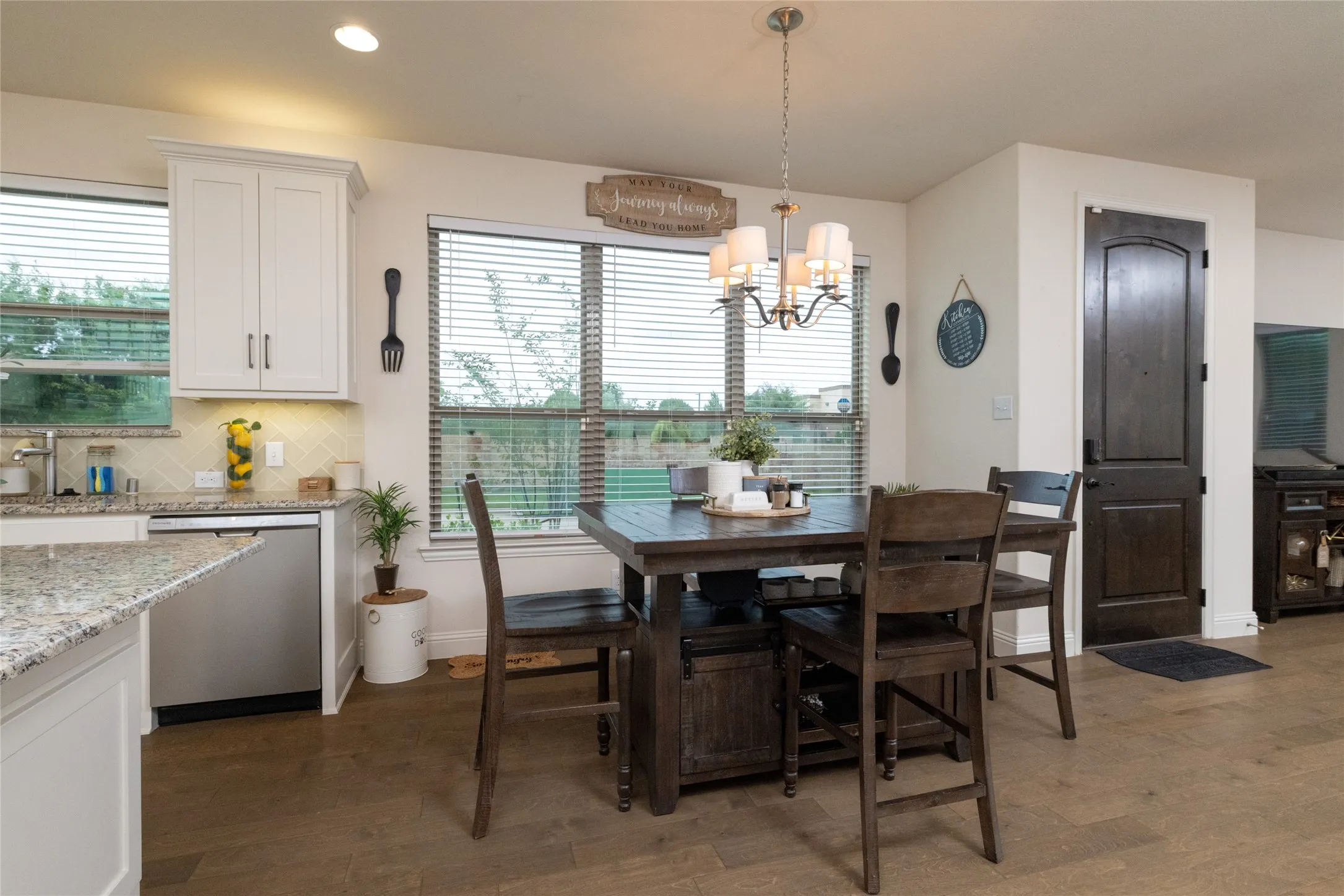 Kitchen dining area featuring a wood-finish floor, white upper cabinetry, and a granite-style countertop