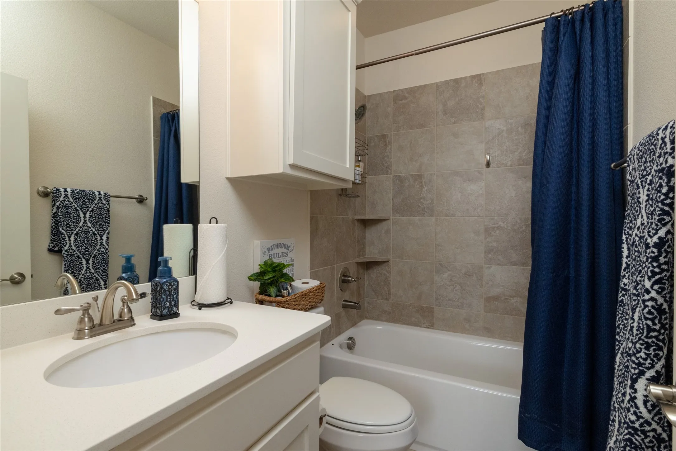 Bathroom featuring a white vanity with an oval undermount sink, brushed nickel faucet, and a light-toned countertop