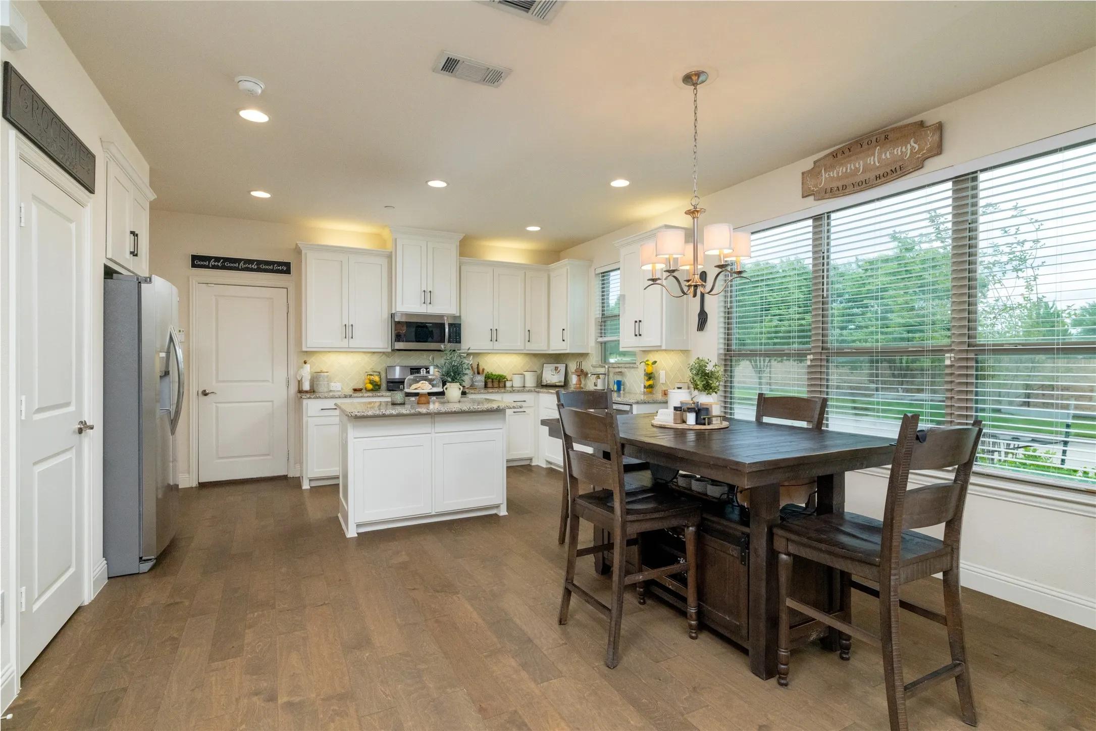 Open-concept kitchen with white cabinetry, stainless steel appliances, a central island, and wood-finish flooring