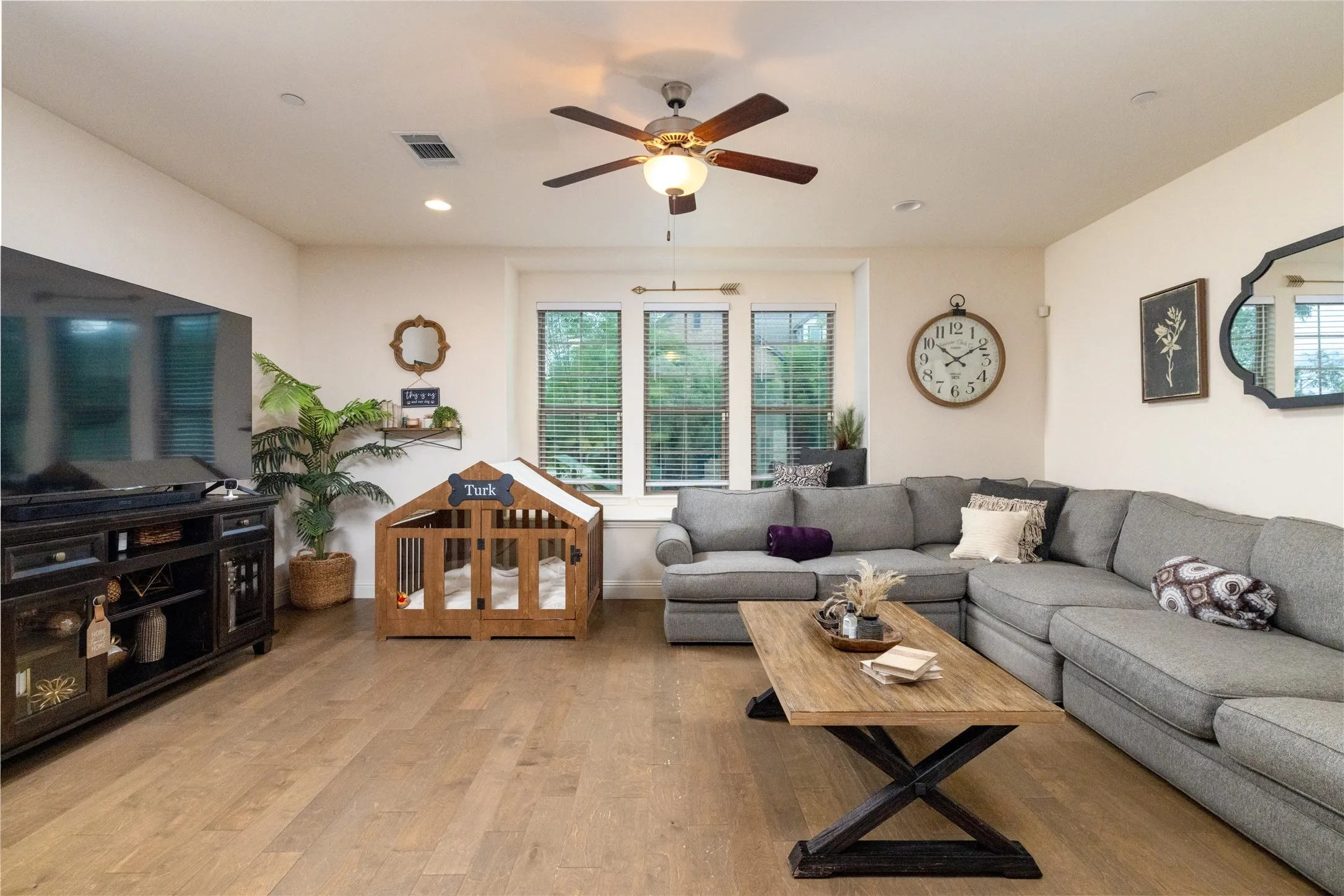 Spacious living area featuring wood-finish flooring, recessed lighting, and a ceiling fan.