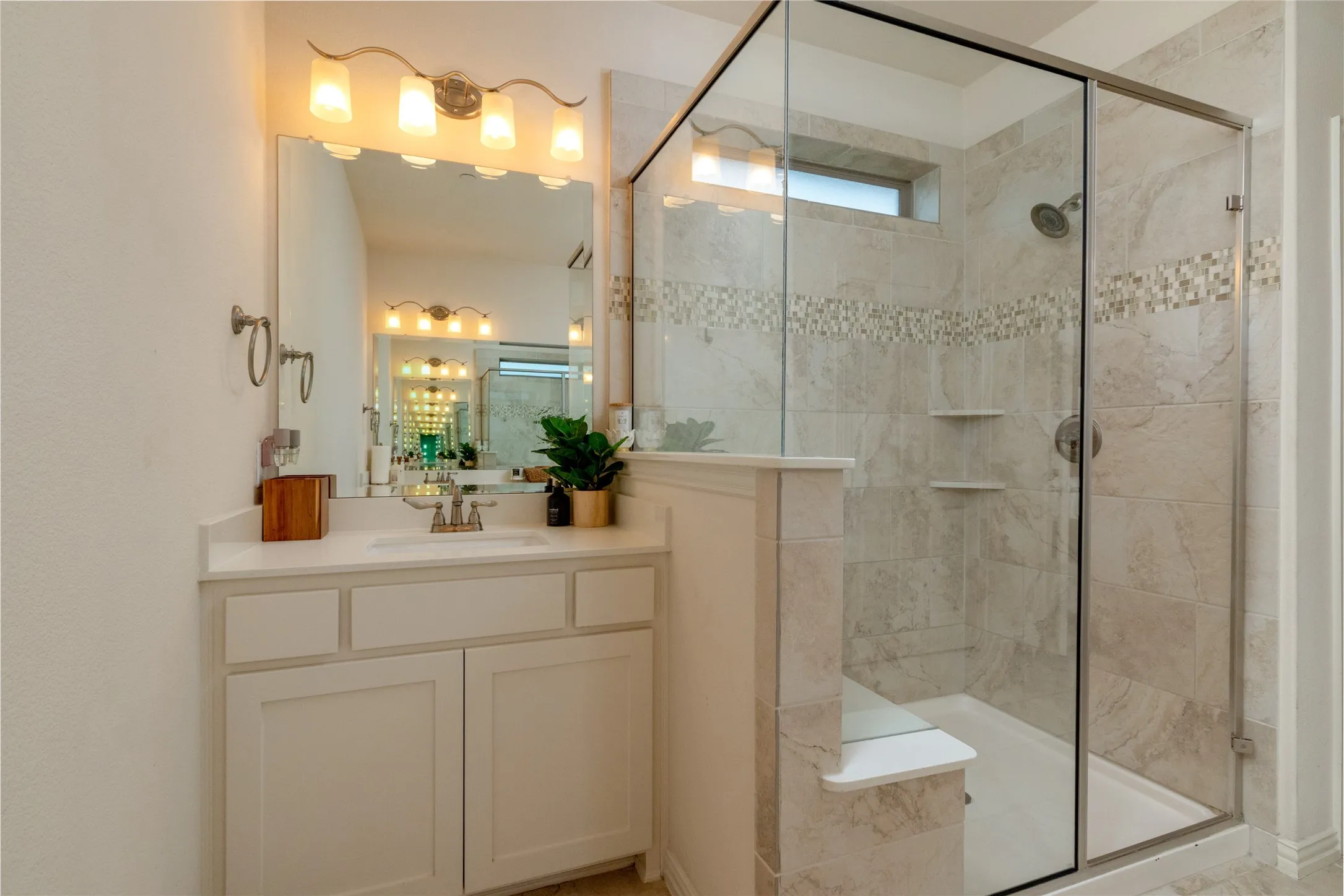 Full bathroom featuring a white vanity with shaker-style cabinetry and a light-toned countertop, a framed mirror, and a four-bulb vanity light fixture