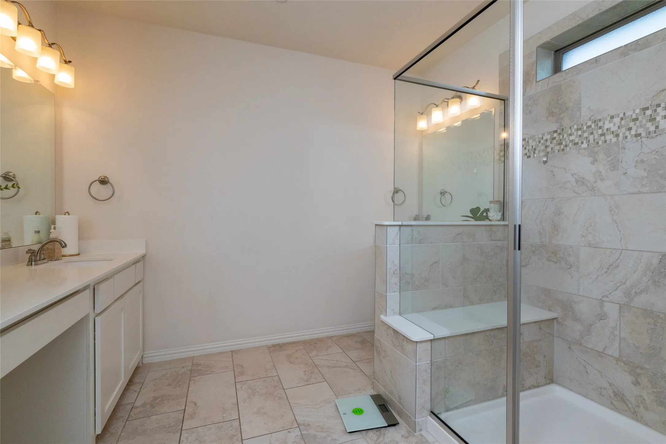 Walk-in shower with glass enclosure, built-in bench, and decorative mosaic tile accent