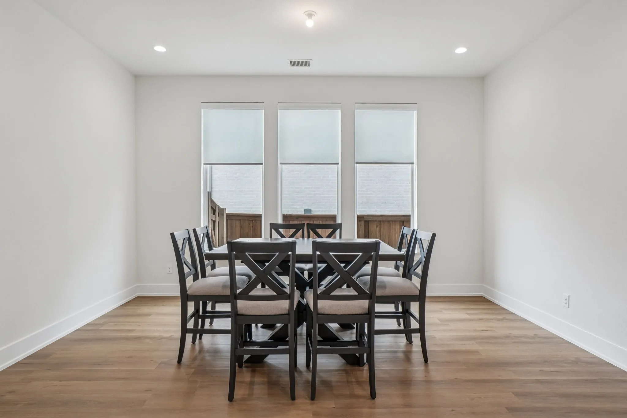 Spacious room featuring wood-finish flooring, crisp white walls, and white baseboards