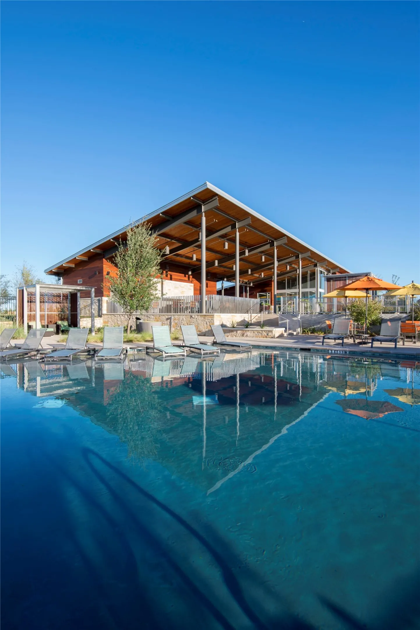 Expansive swimming pool with integrated lounge seating, reflecting a contemporary open-air pavilion