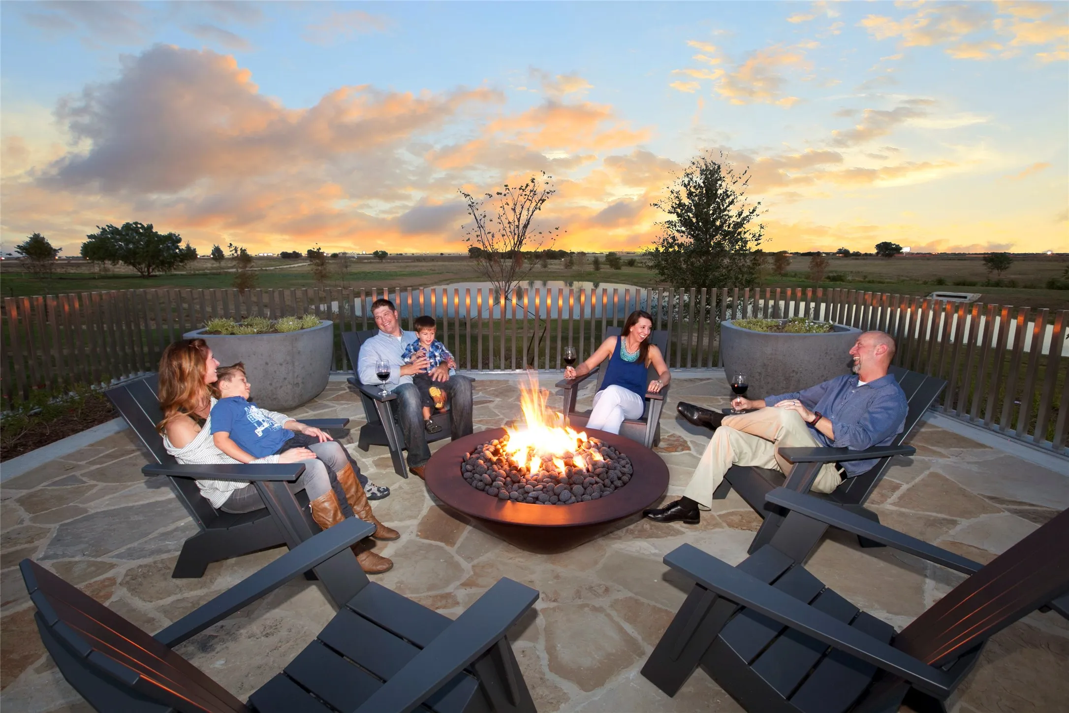 Expansive outdoor patio featuring flagstone paving, a built-in circular fire pit, and durable fencing