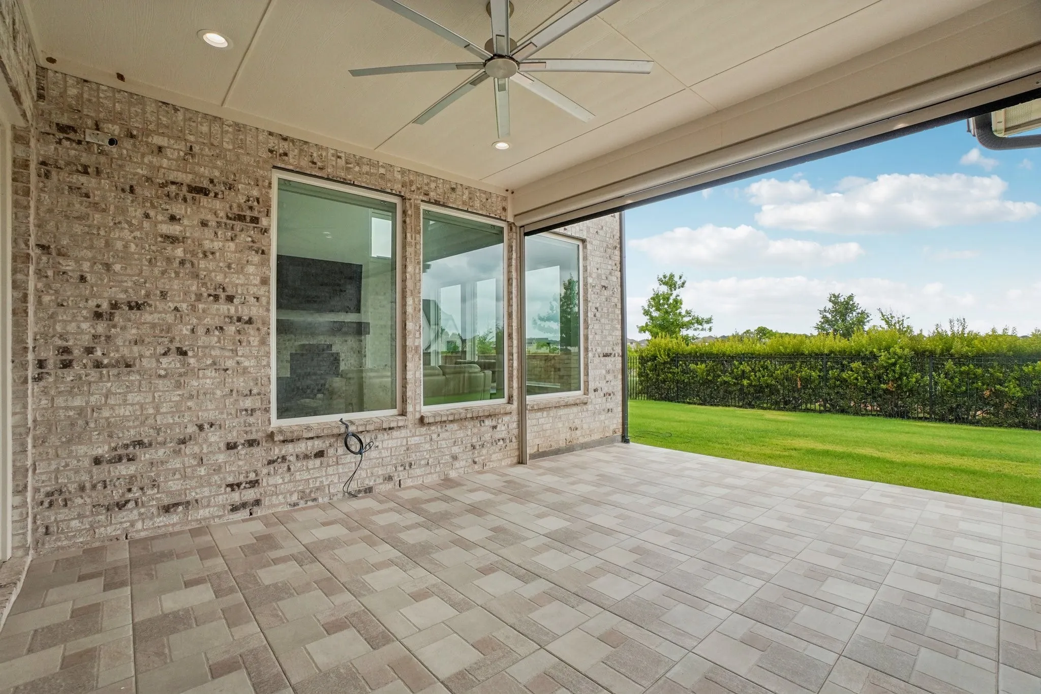 Expansive covered patio featuring brick exterior walls, recessed lighting, and a ceiling fan
