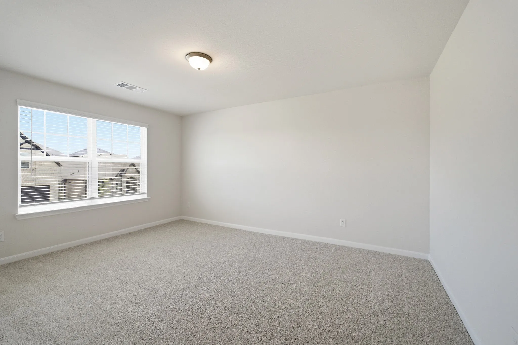 Neutral toned room featuring plush carpet flooring and a large window with white blinds