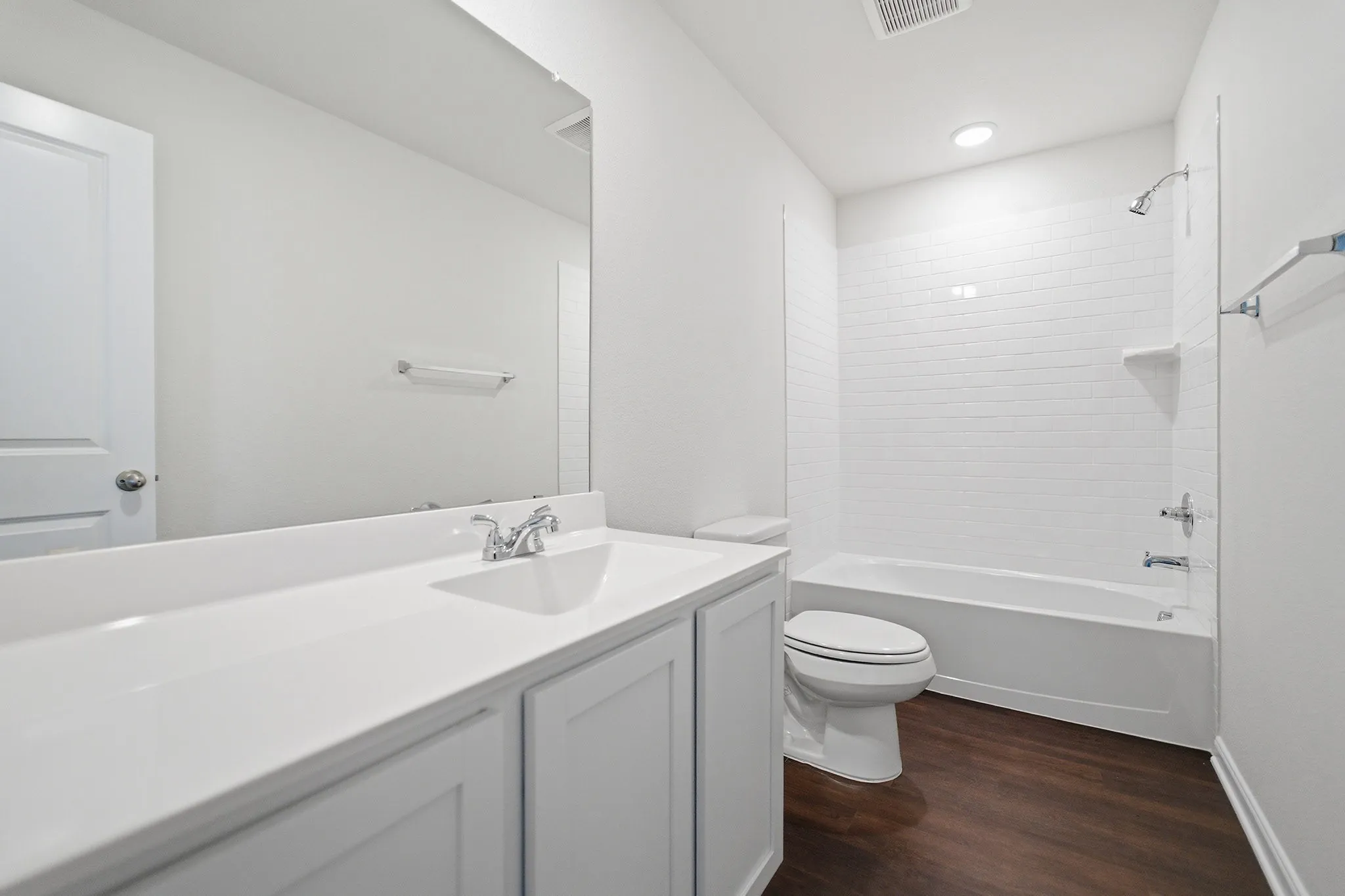 Bathroom featuring a white vanity with integrated sink, chrome faucet, and expansive wall mirror