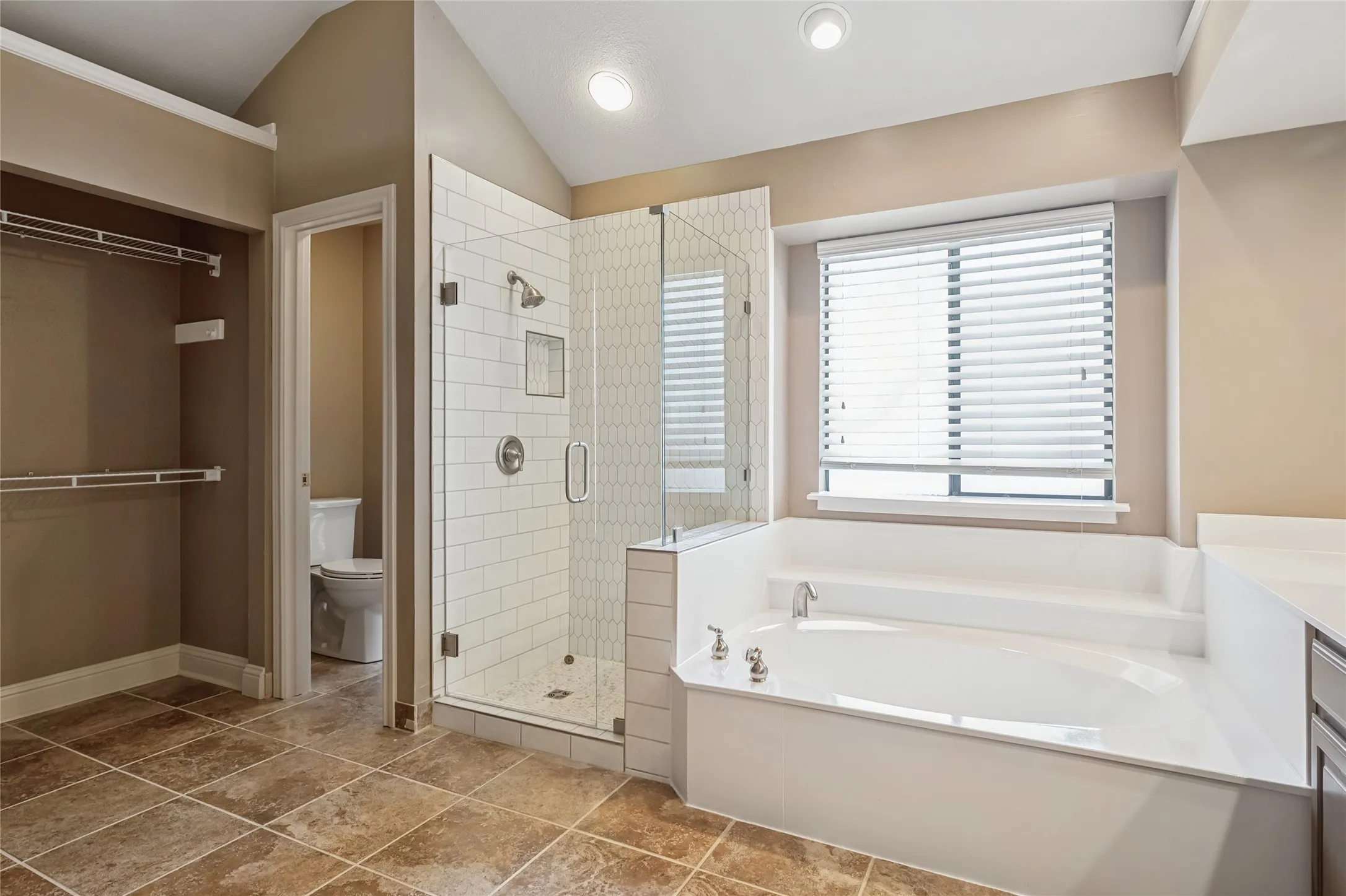 Full bath with a garden tub, lofted ceiling, toilet, a stall shower, and baseboards
