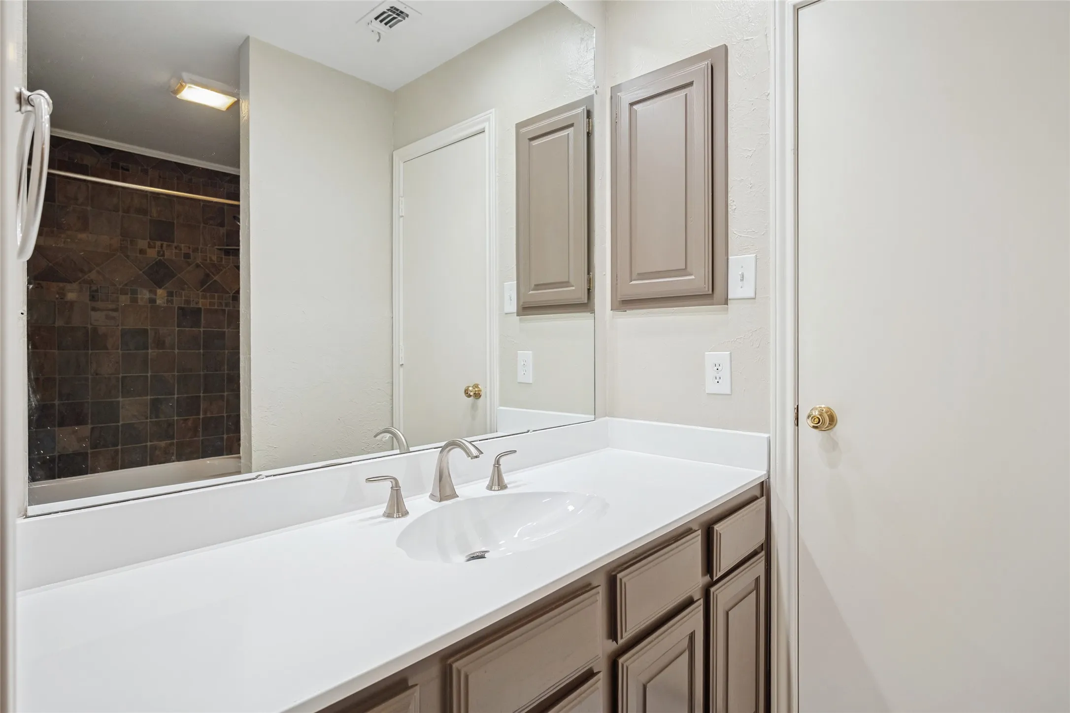 Bathroom with a shower, visible vents, and vanity