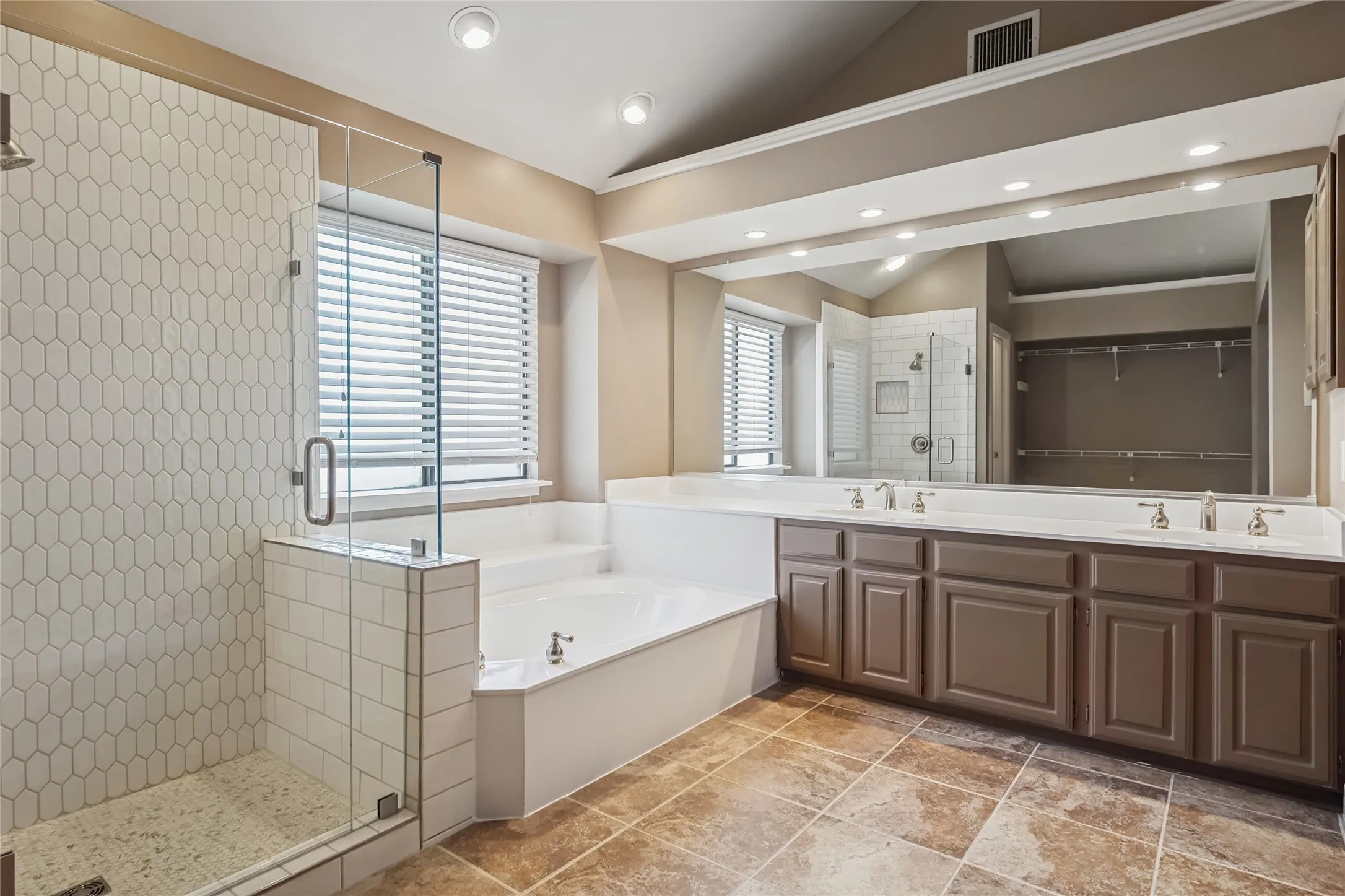 Bathroom featuring a sink, visible vents, vaulted ceiling, a bath, and a stall shower