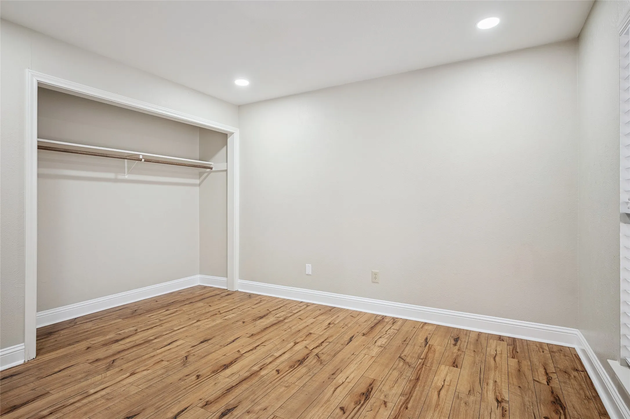 Unfurnished bedroom featuring a closet, baseboards, hardwood / wood-style floors, and recessed lighting