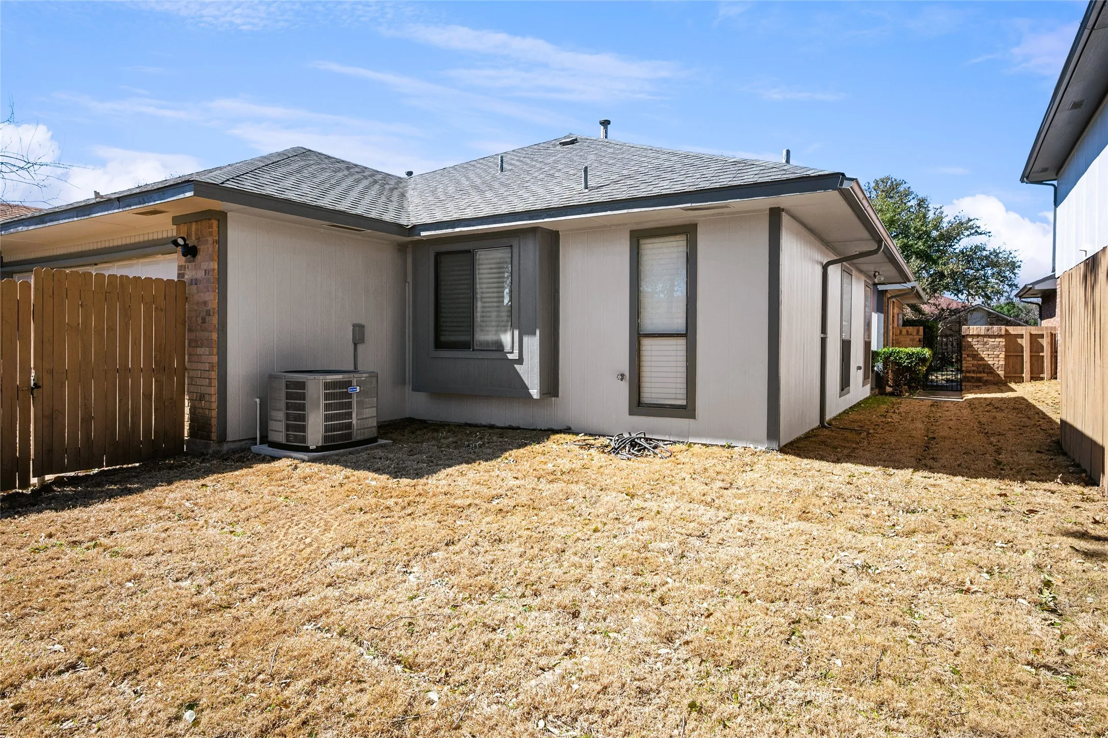 Rear view of house with a garage, a fenced backyard, central AC unit, and a shingled roof