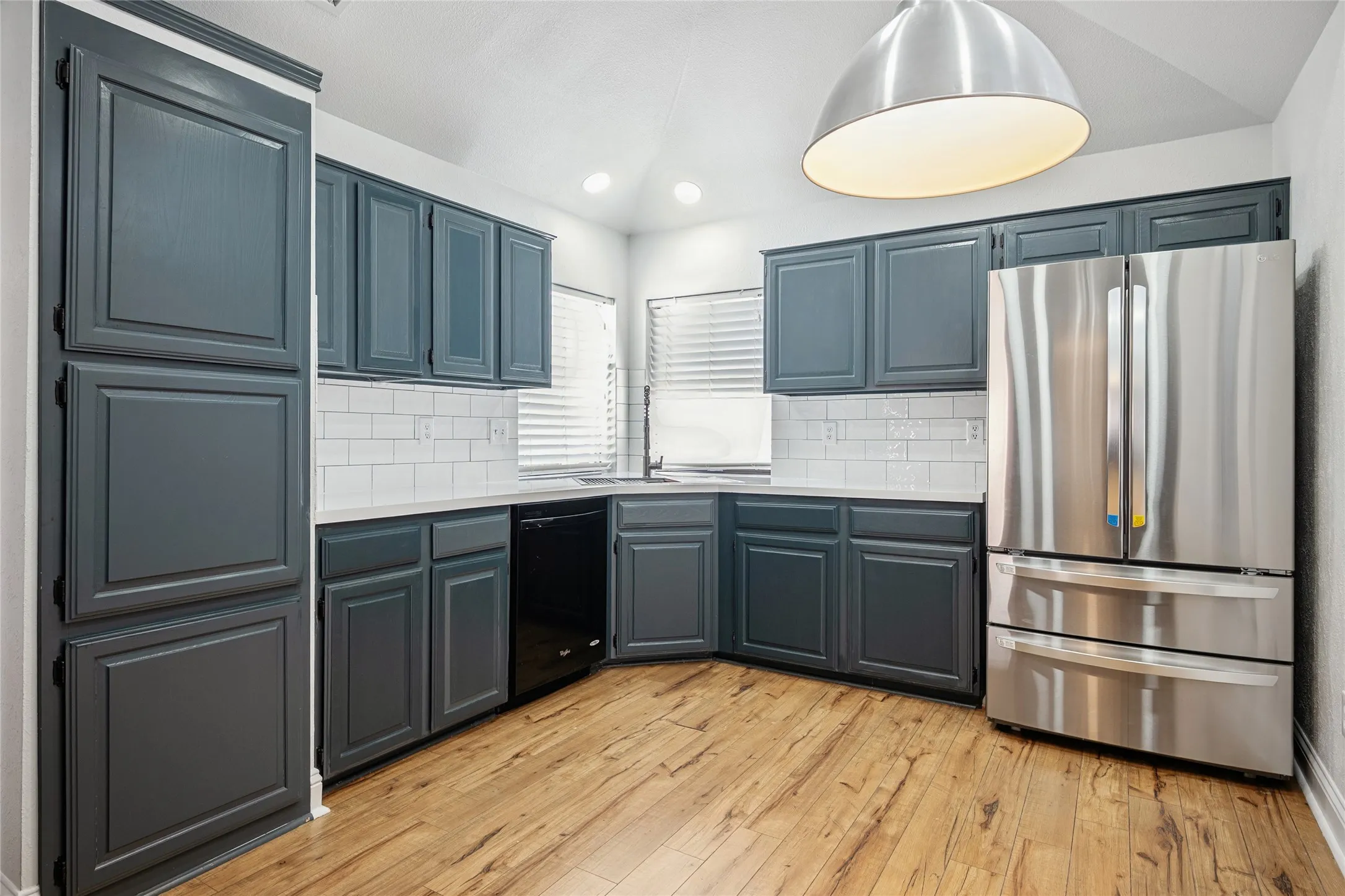 Kitchen featuring tasteful backsplash, freestanding refrigerator, light countertops, and light wood-style flooring