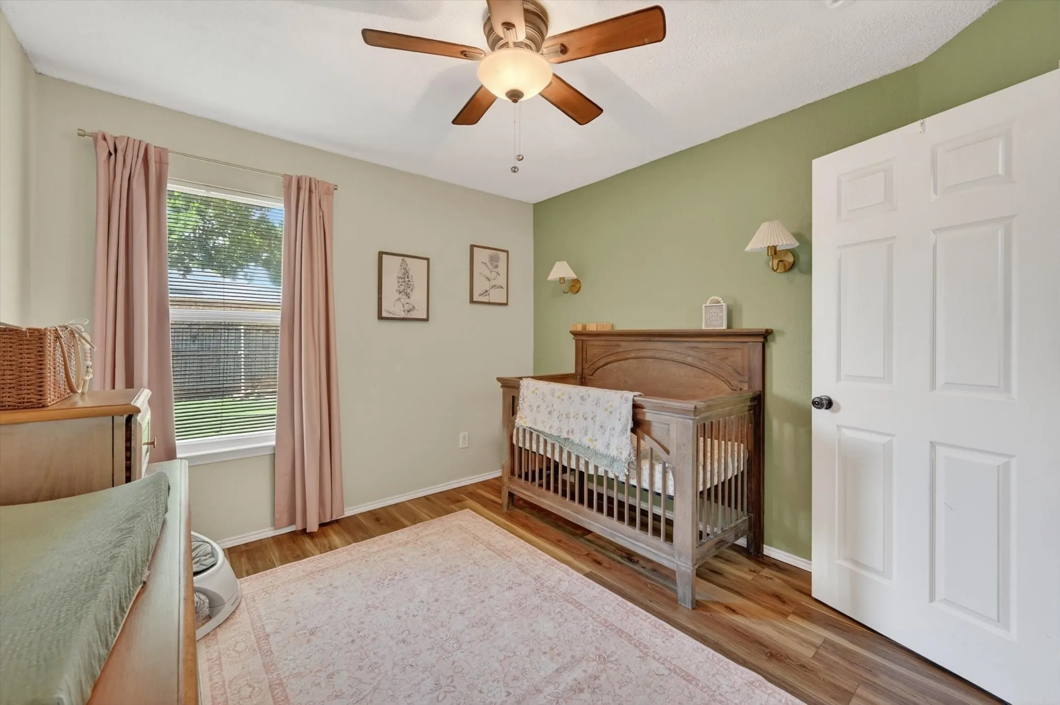 Interior room featuring wood-finish flooring, a ceiling fan with integrated lighting, and a paneled white door