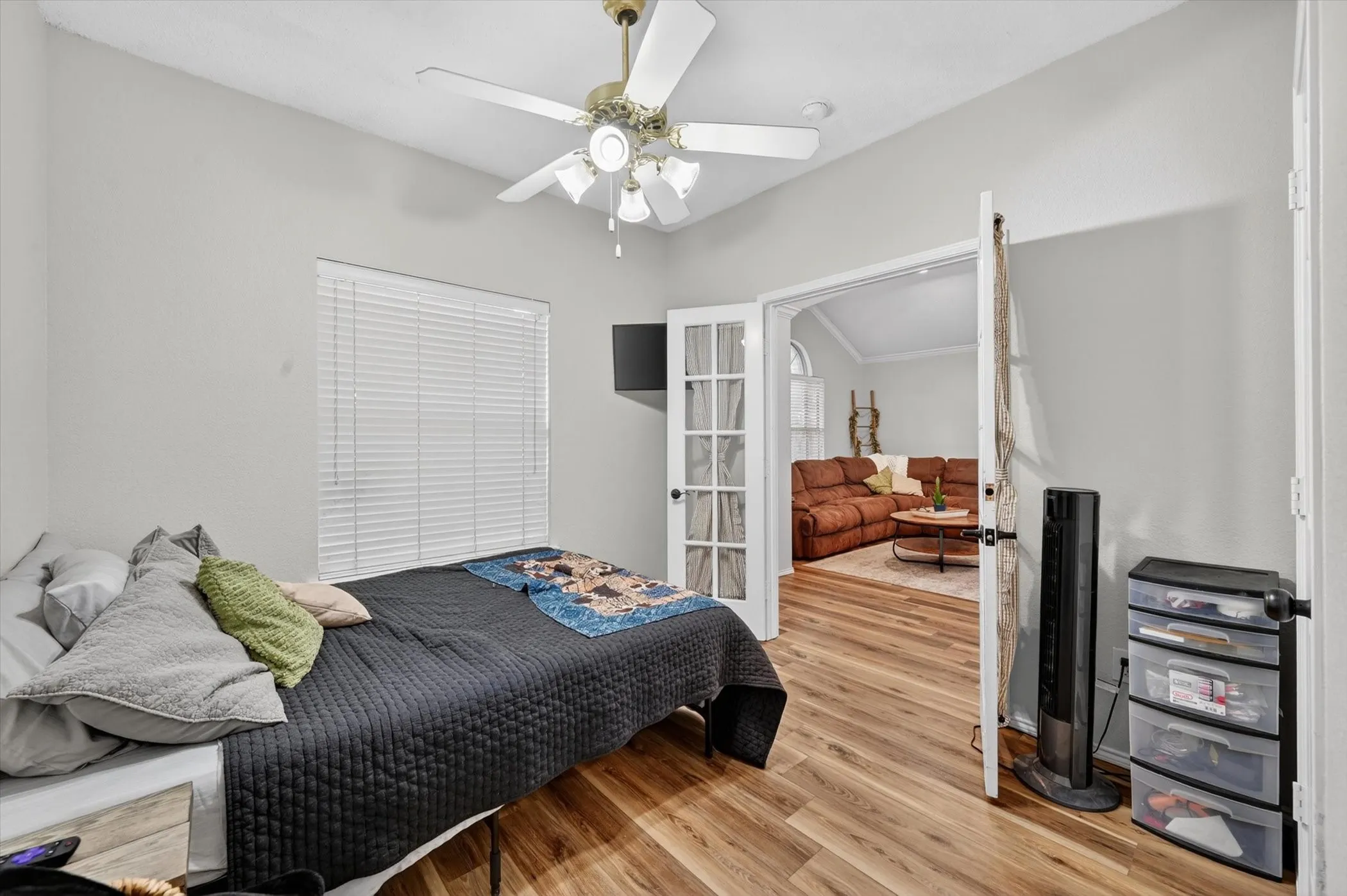 Room featuring wood-finish flooring, a ceiling fan with light fixture, and a window with blinds