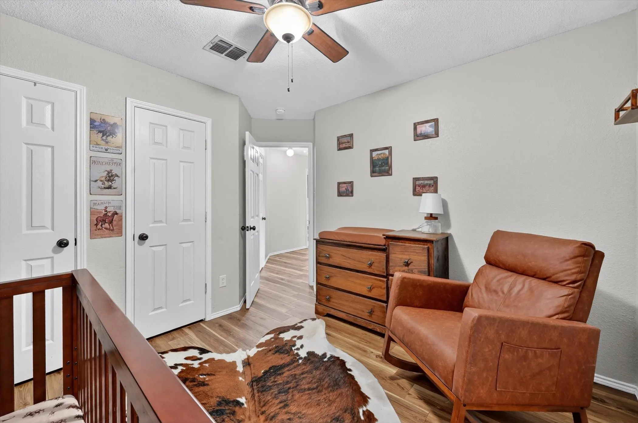 Hallway featuring wood-finish flooring, light gray walls, white paneled doors, and a ceiling fan with integrated lighting