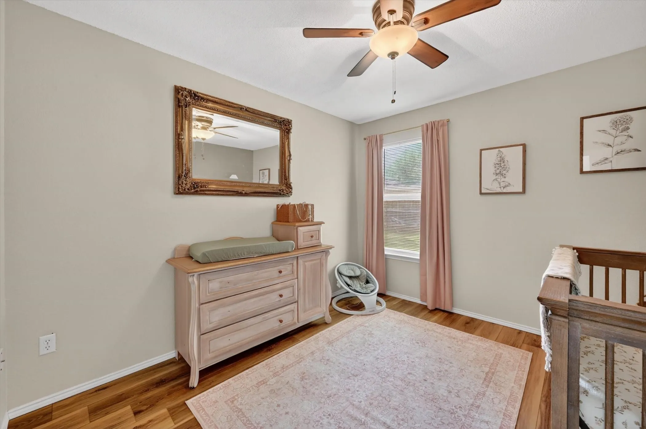Room featuring wood-finish flooring, a ceiling fan with integrated lighting, and a single window with vertical blinds