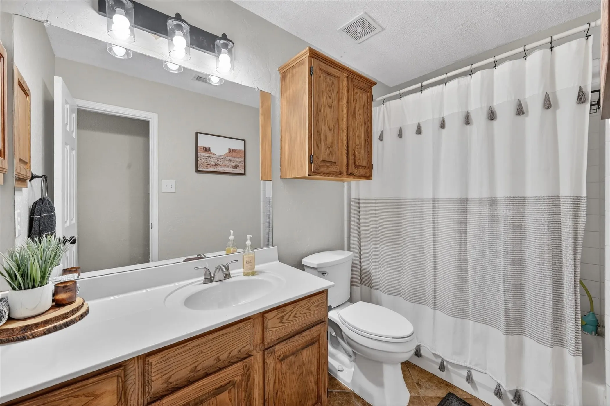 Bathroom featuring a wood-finish vanity with an integrated white sink, a chrome two-handle faucet, and a large wall-mounted mirror