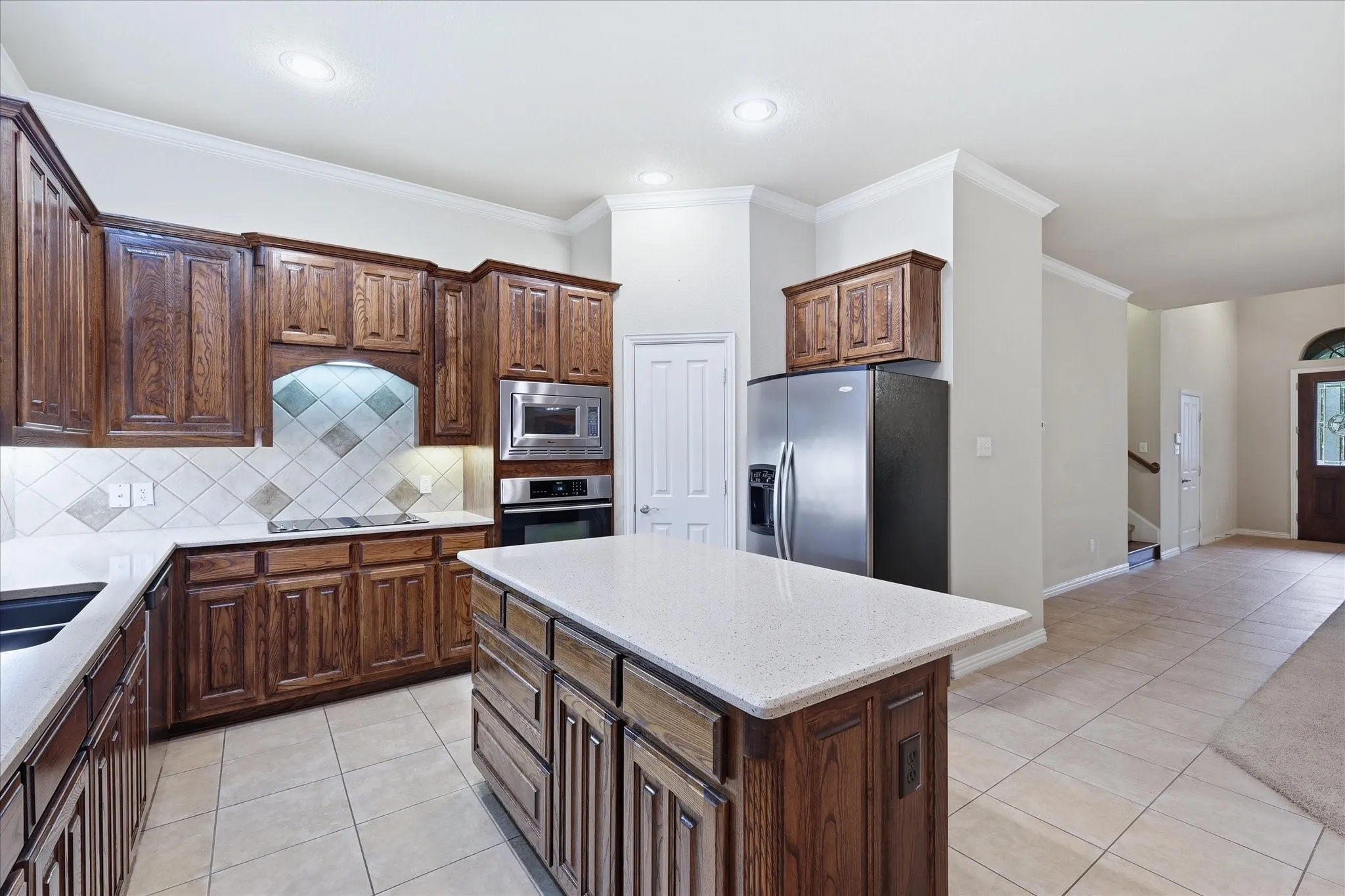 Island features ample storage and bar seating. Electric Jenn-Air cooktop has downdraft exhaust. Under the counter lights round out this perfect space.