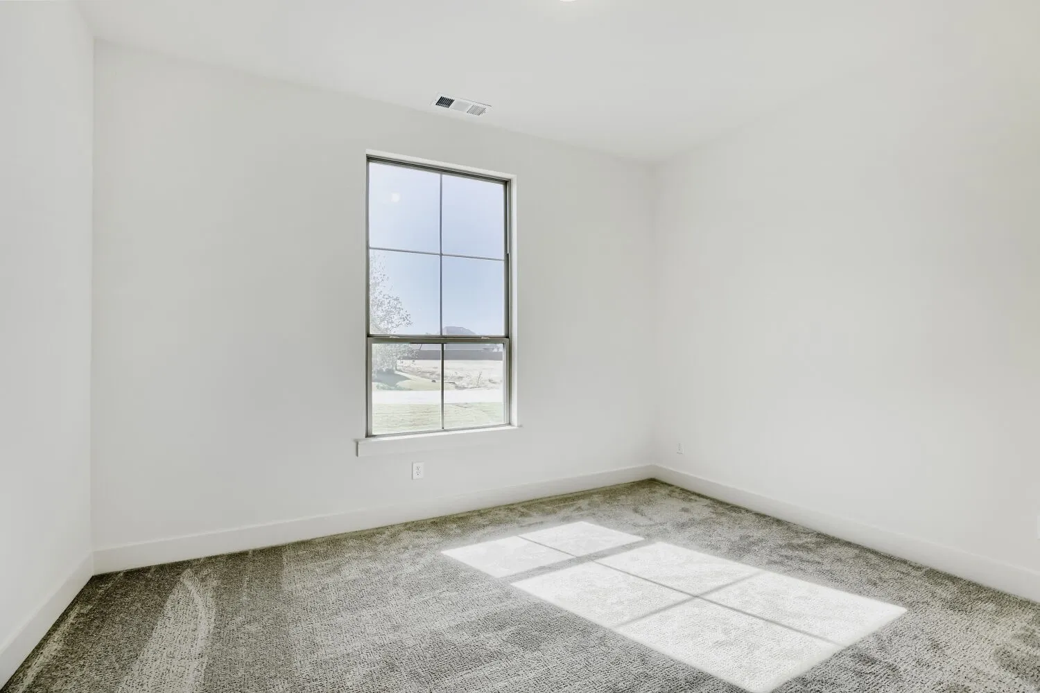 Expansive window, neutral wall palette, recessed lighting, and textured carpeting