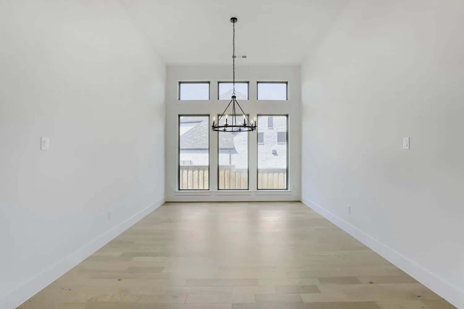 Hardwood-finish flooring, high ceilings, chandelier lighting, and a window wall with transom windows