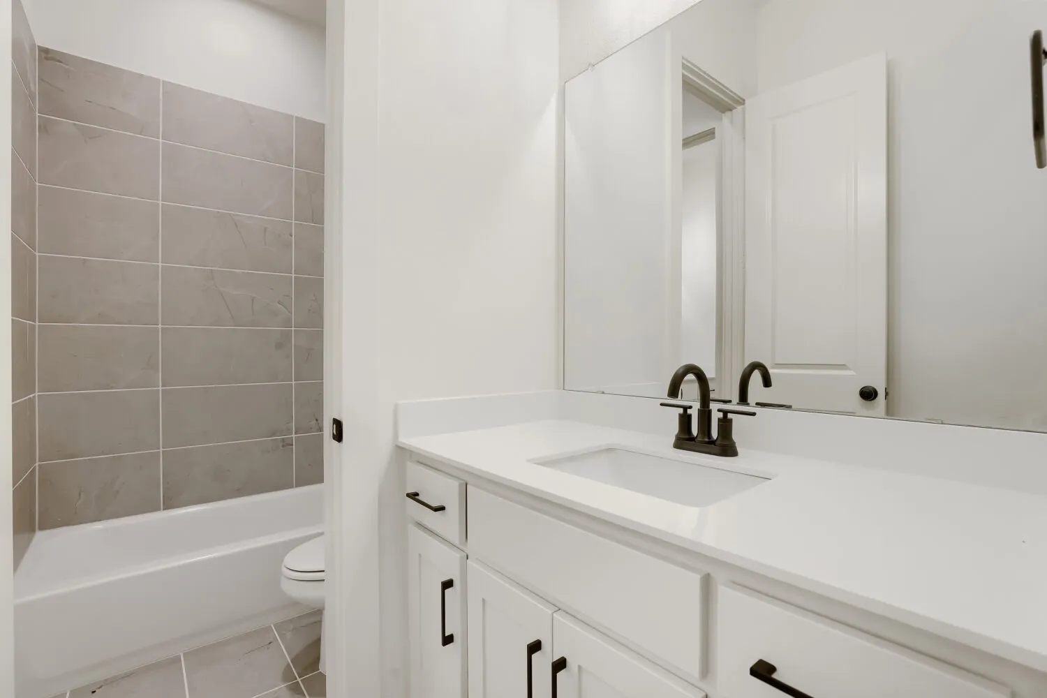 White vanity with integrated sink, bronze-finish faucet, and coordinating hardware