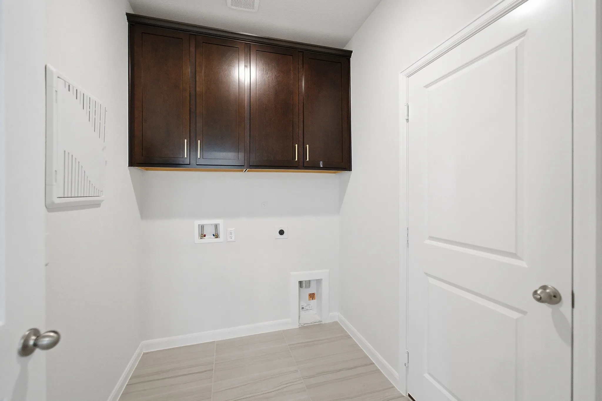 Dedicated utility space featuring ample wall cabinetry, light-toned flooring, white baseboards, and a paneled interior door