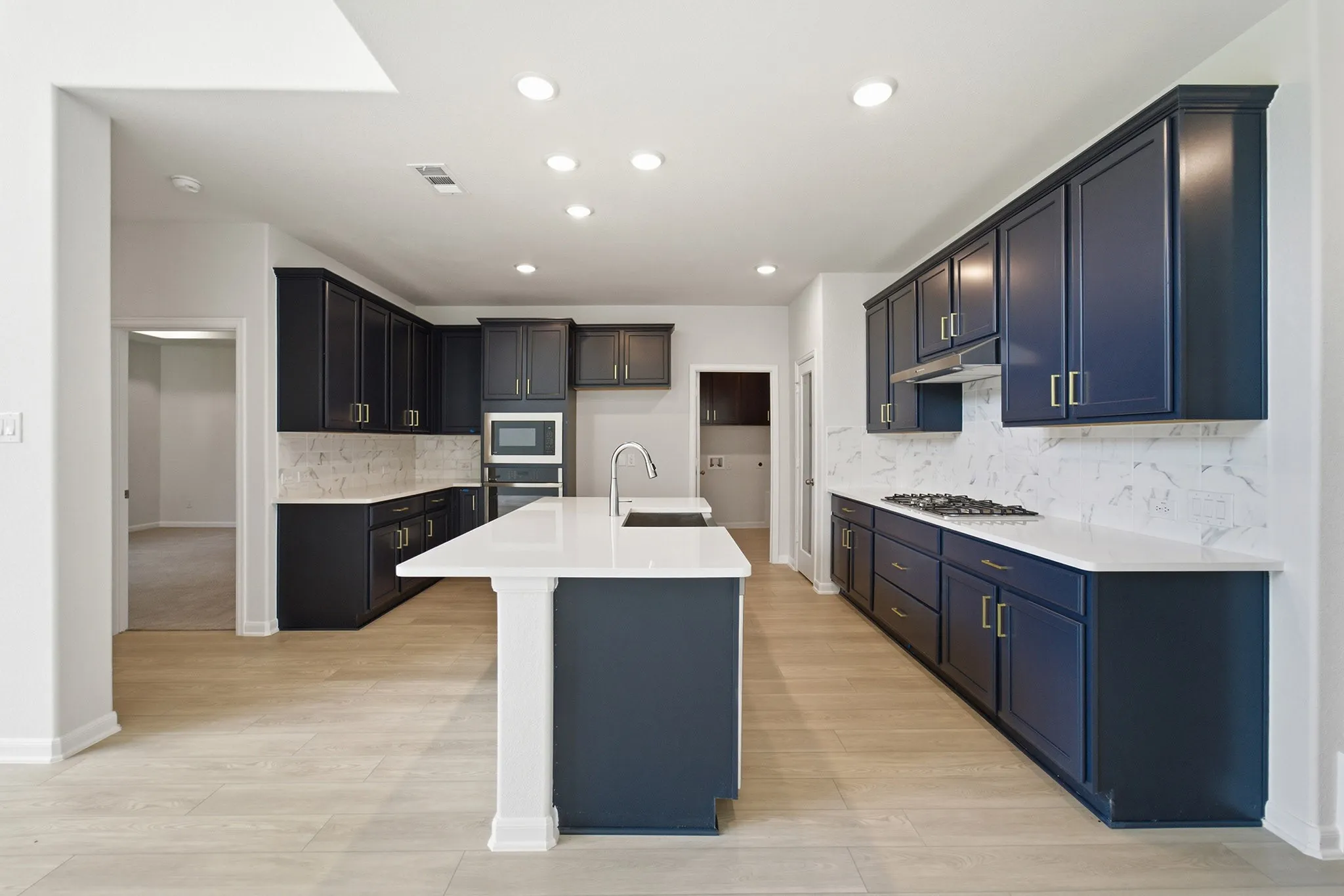Modern kitchen featuring dark blue cabinetry, white countertops, a large center island, wood-finish flooring, and recessed lighting