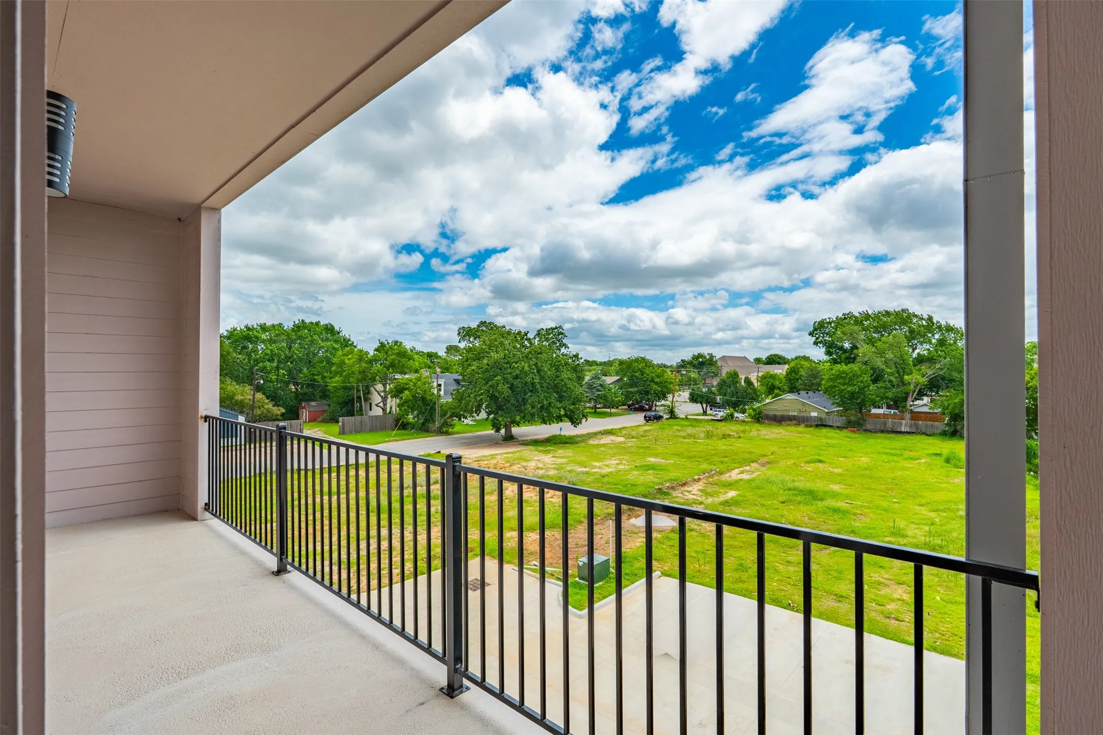 Private balcony featuring concrete flooring and a black metal railing
