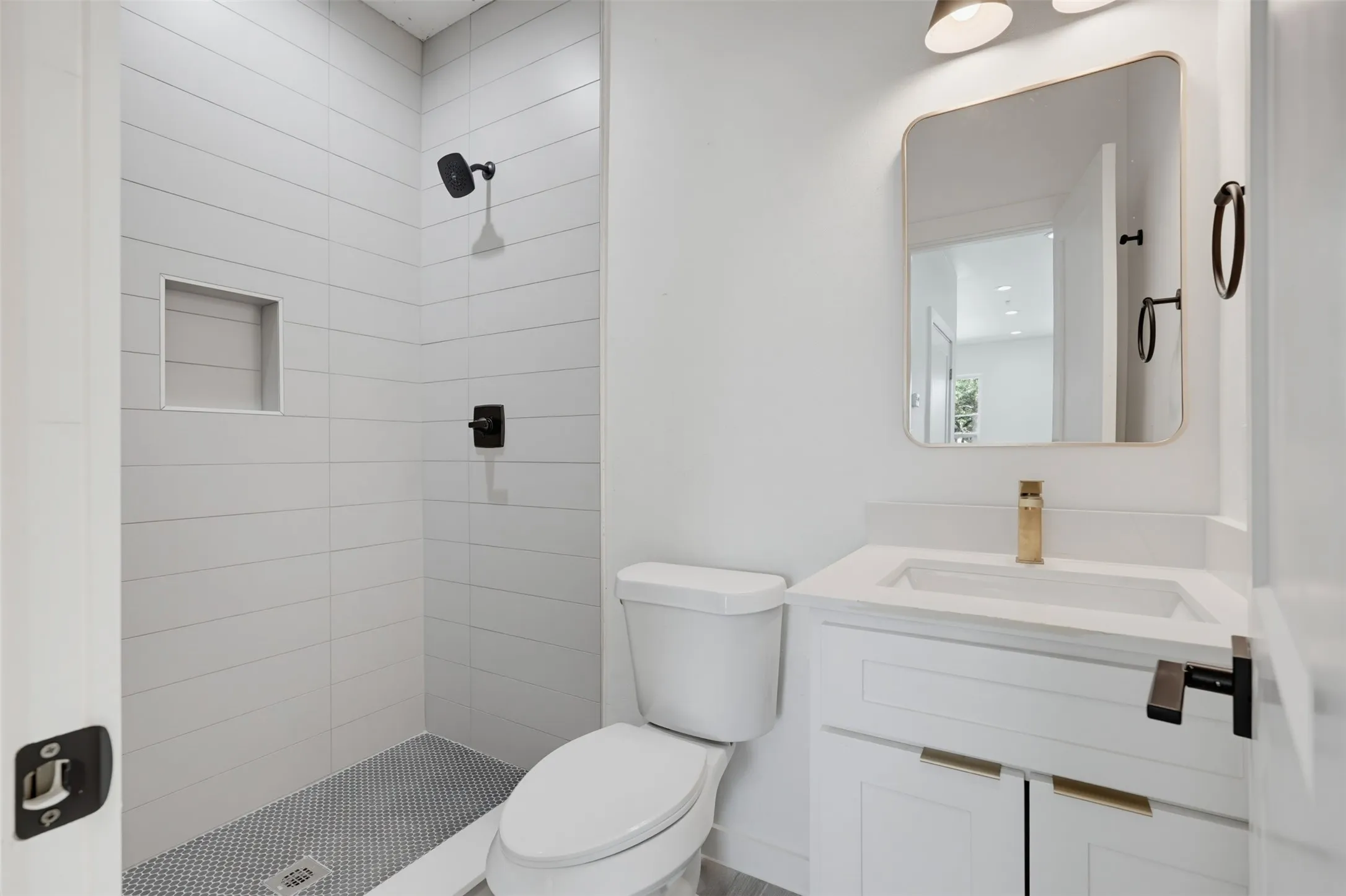Bathroom featuring a walk-in shower with horizontal white tile, an integrated shower niche, and a contrasting penny tile floor
