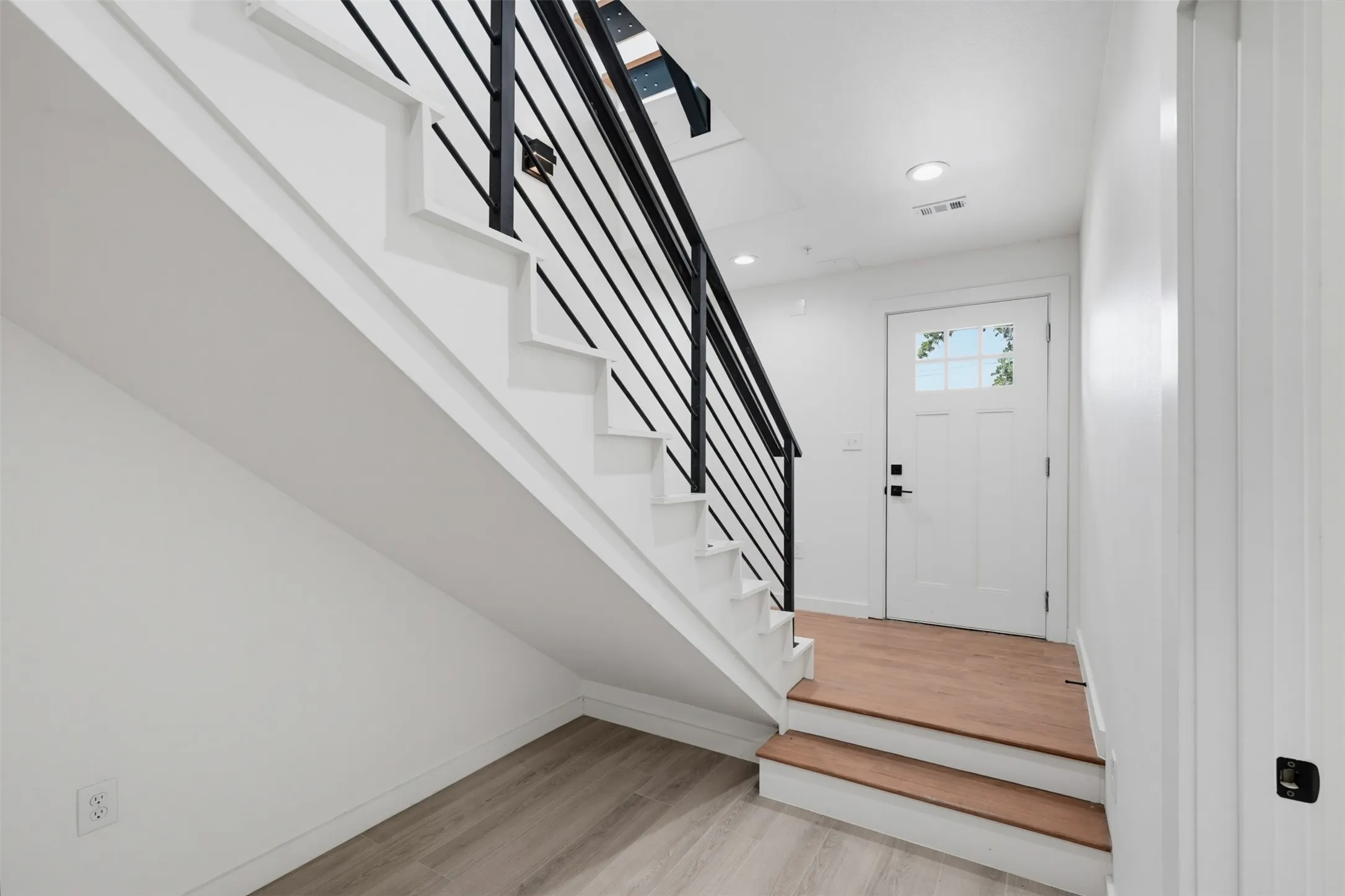 Contemporary staircase with black metal horizontal railings and light wood-finish treads