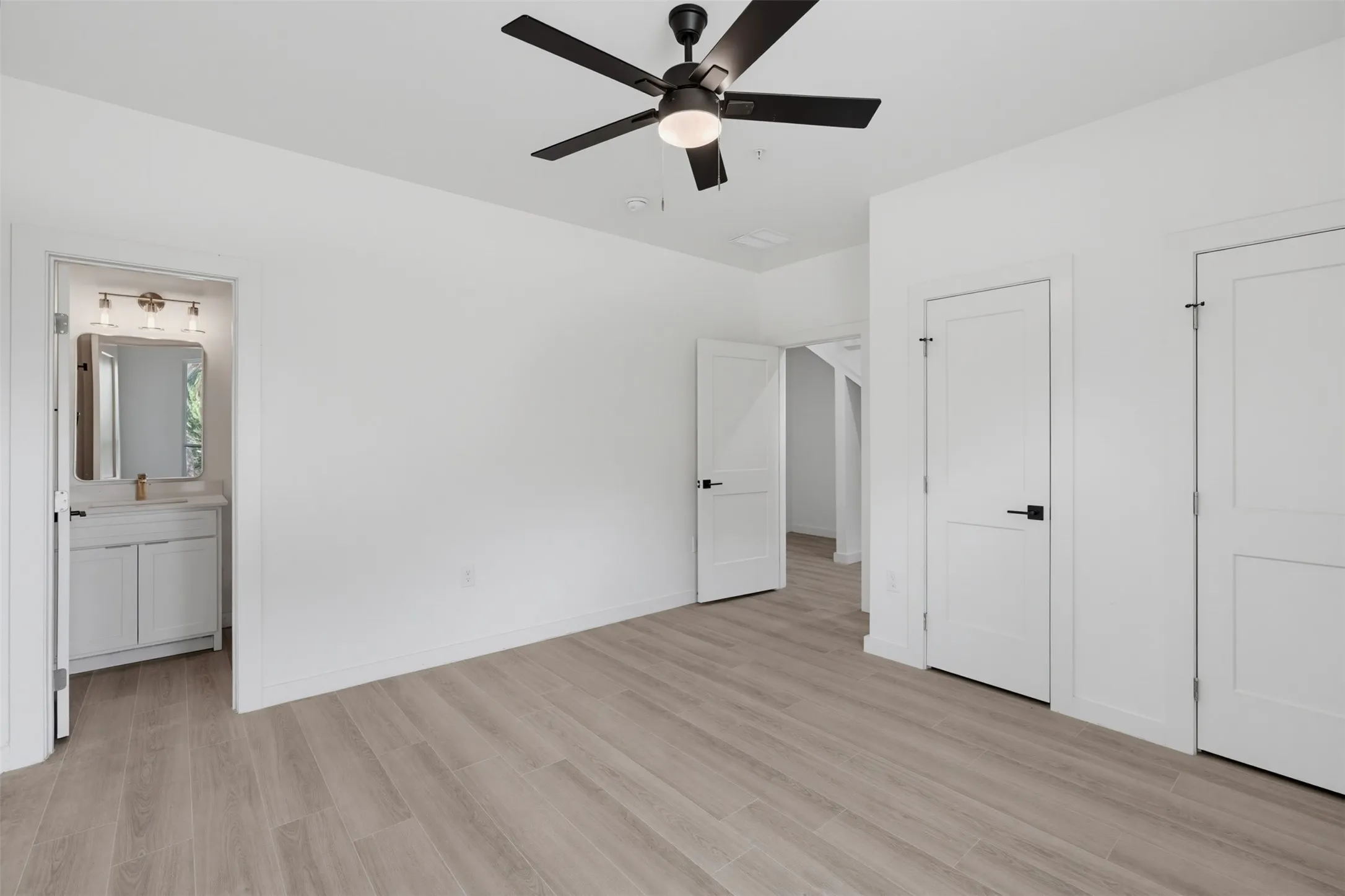 Spacious room featuring wood-finish flooring and a contemporary ceiling fan