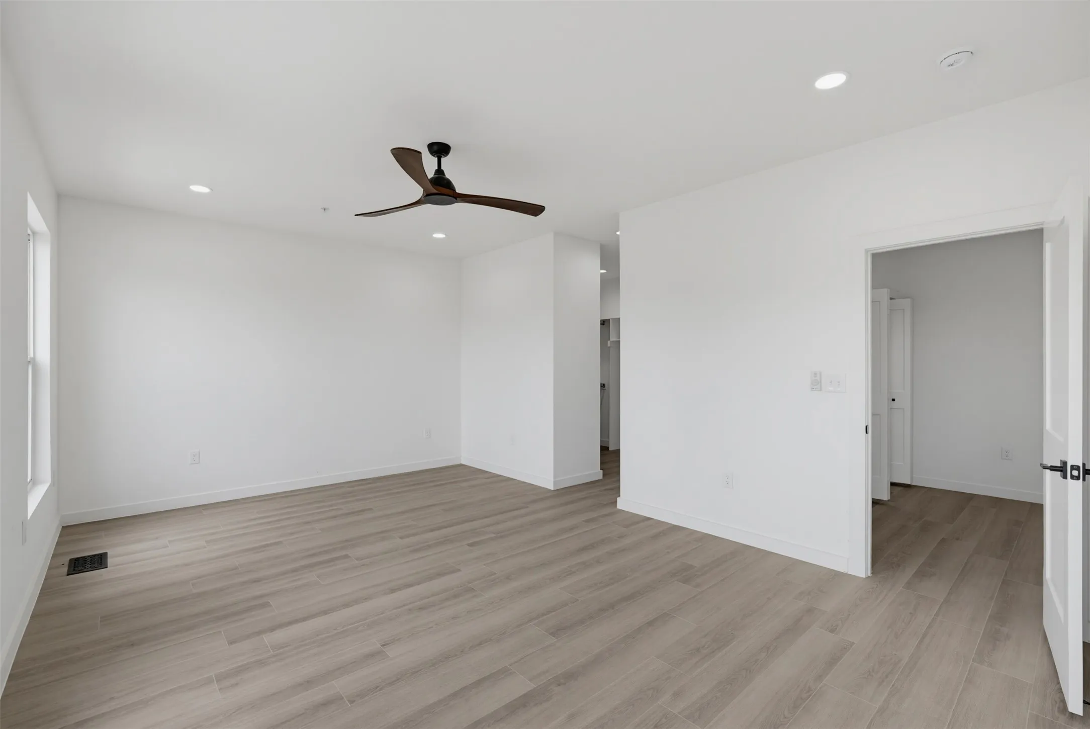 Spacious interior featuring wood-finish flooring, a modern ceiling fan, recessed lighting, and white trim