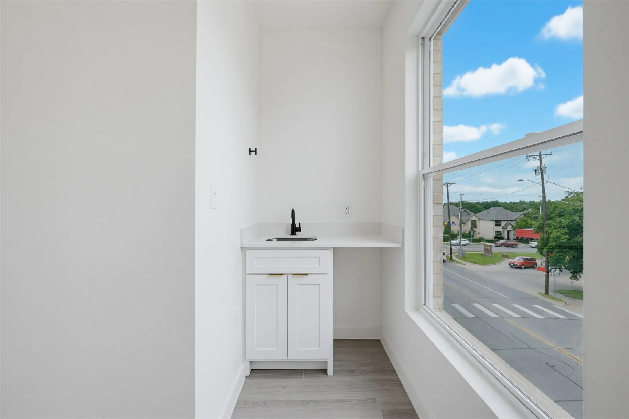 Bright space featuring a white vanity cabinet with gold-finish pulls, a light countertop, and a black faucet