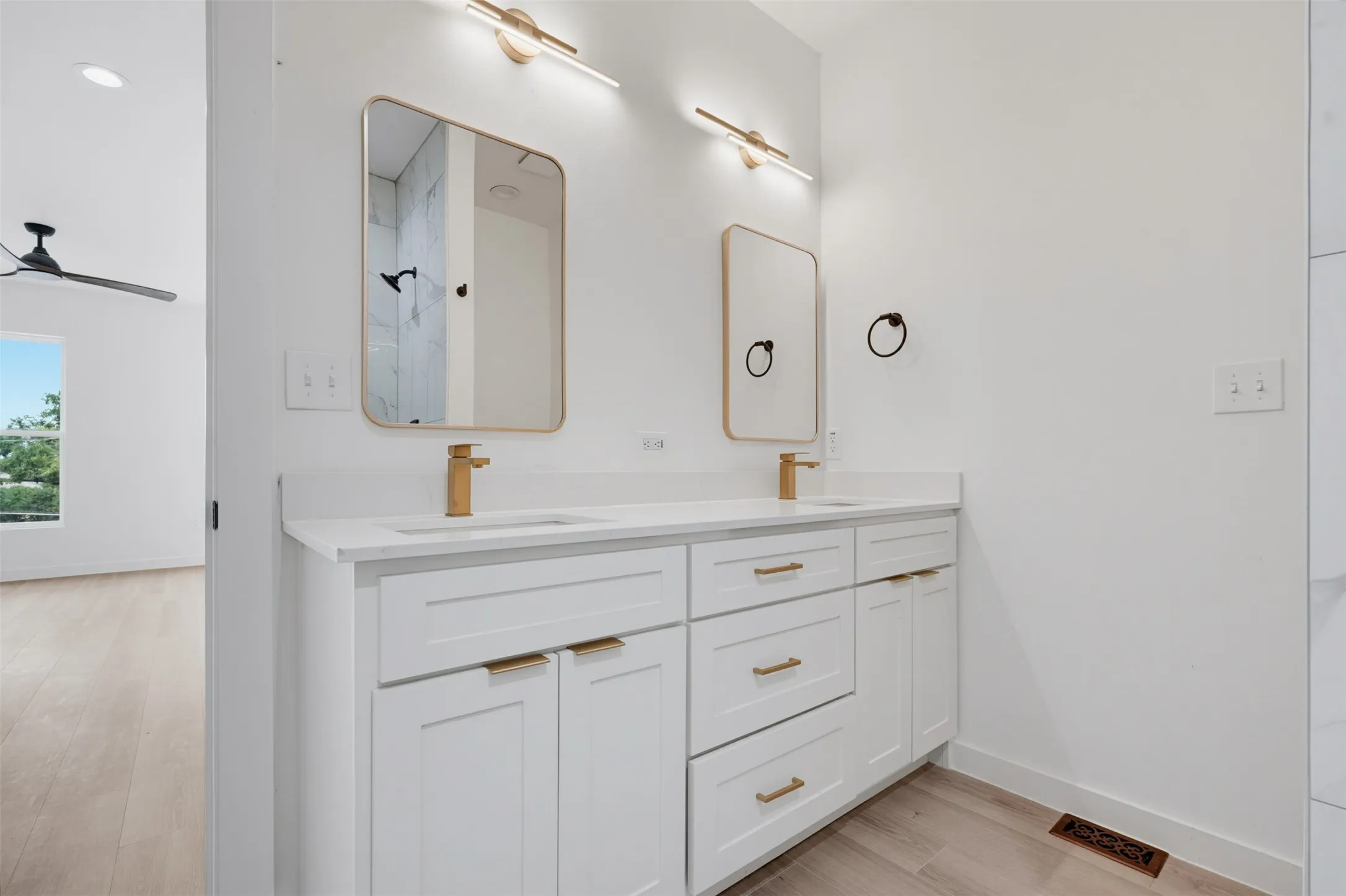 Double vanity with white cabinetry, gold-toned hardware, and rectangular framed mirrors
