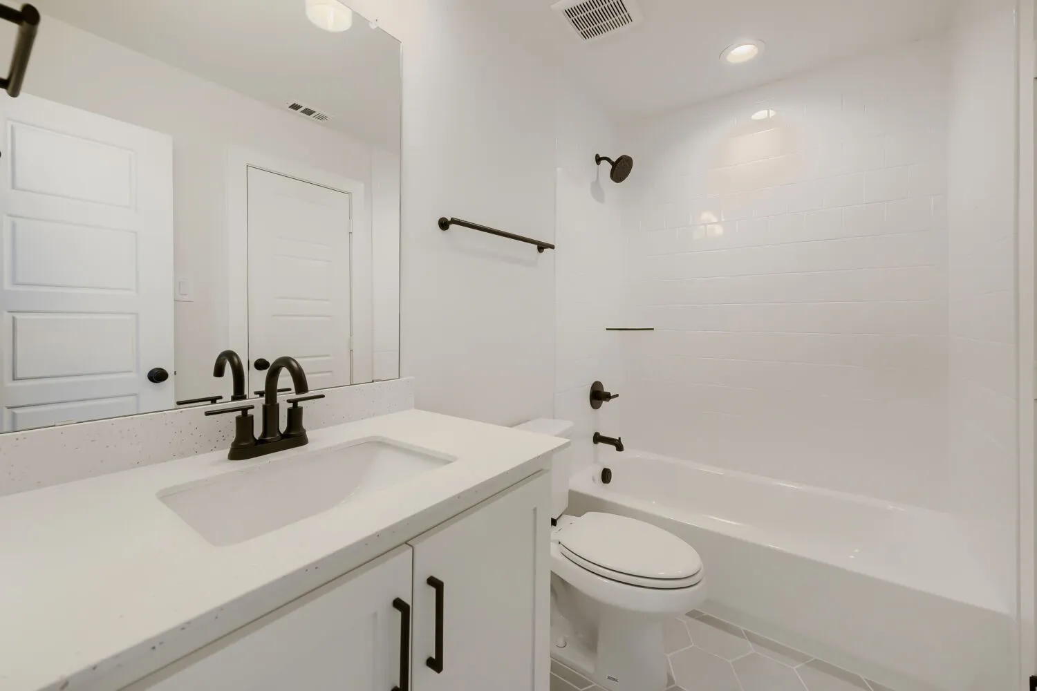 White vanity with an integrated sink, speckled countertop, and dark-finish faucet