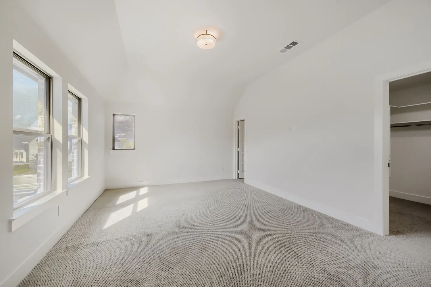 Vaulted ceiling, recessed lighting, wall-to-wall carpeting, multiple windows, and a built-in closet with shelving