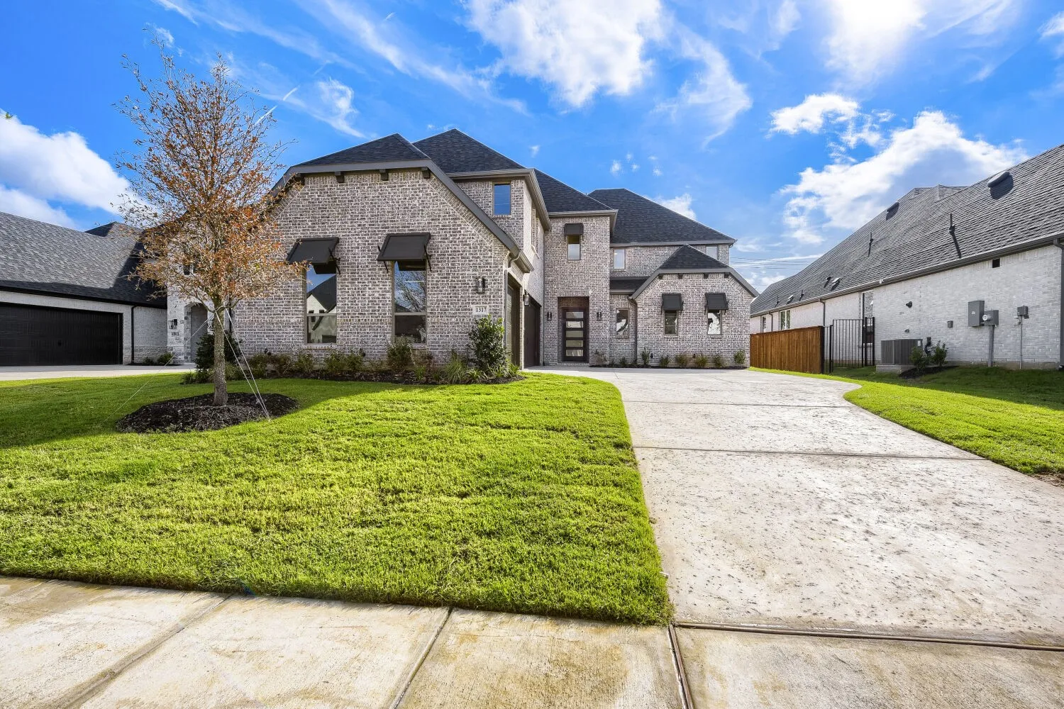 Brick exterior with dark roof shingles, an attached garage, a contemporary front entry door, and a concrete driveway