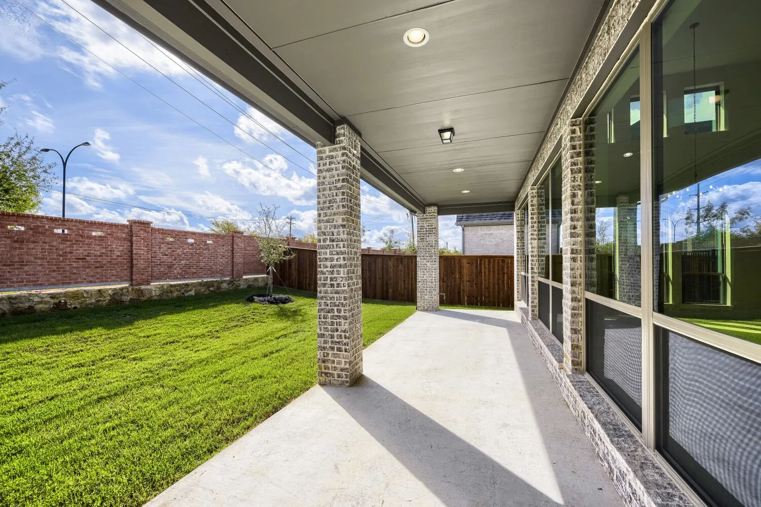 Covered concrete patio with brick pillars and recessed lighting